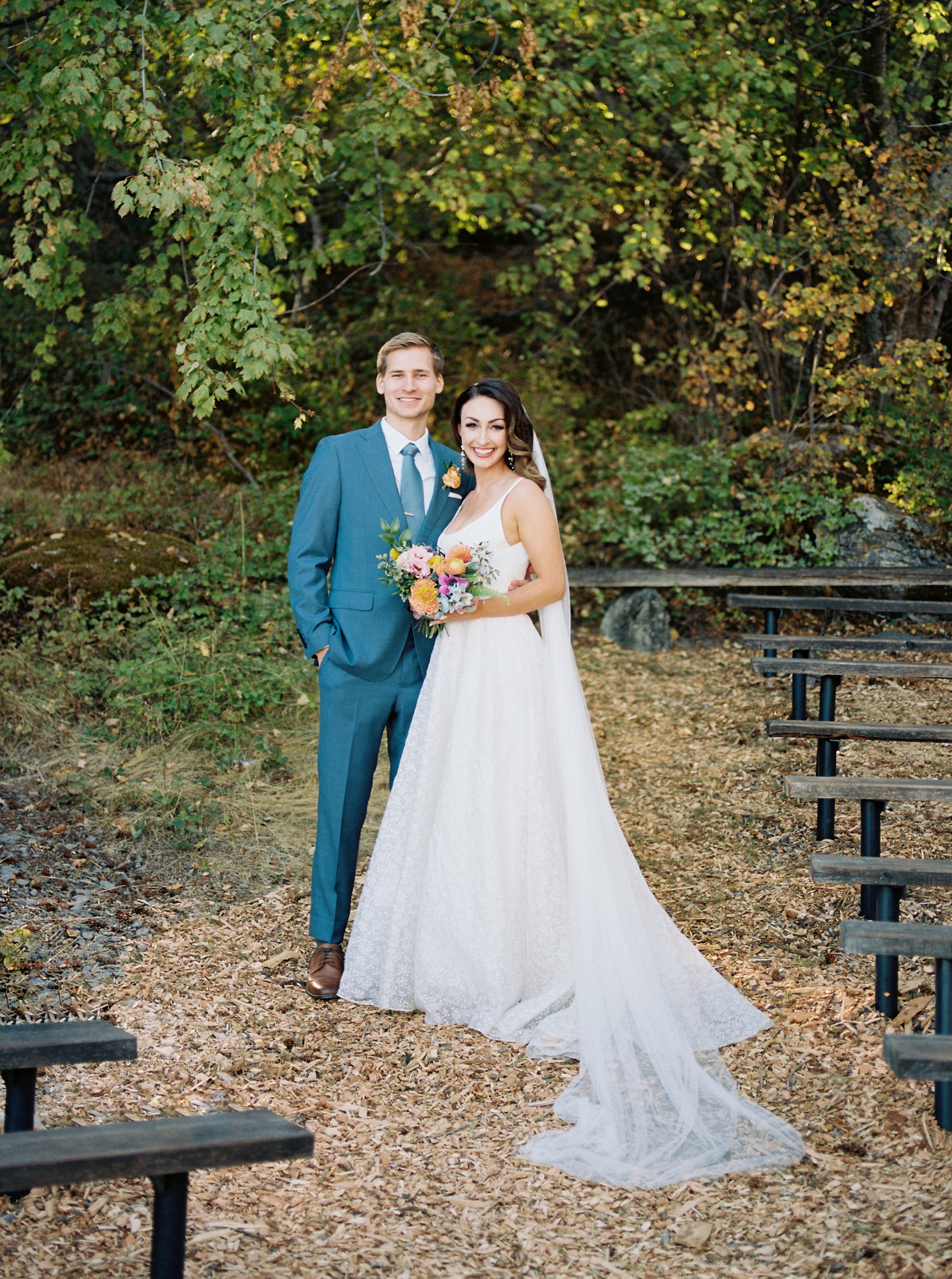 Jeune couple de mariés se tenant l'un contre l'autre la femme avec son bouquet, sa robe blanche et ces accessoires de mariage