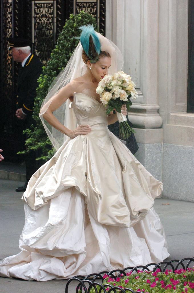 Carrie Bradshow dans sa robe de mariée luxe sentant son bouquet de mariage