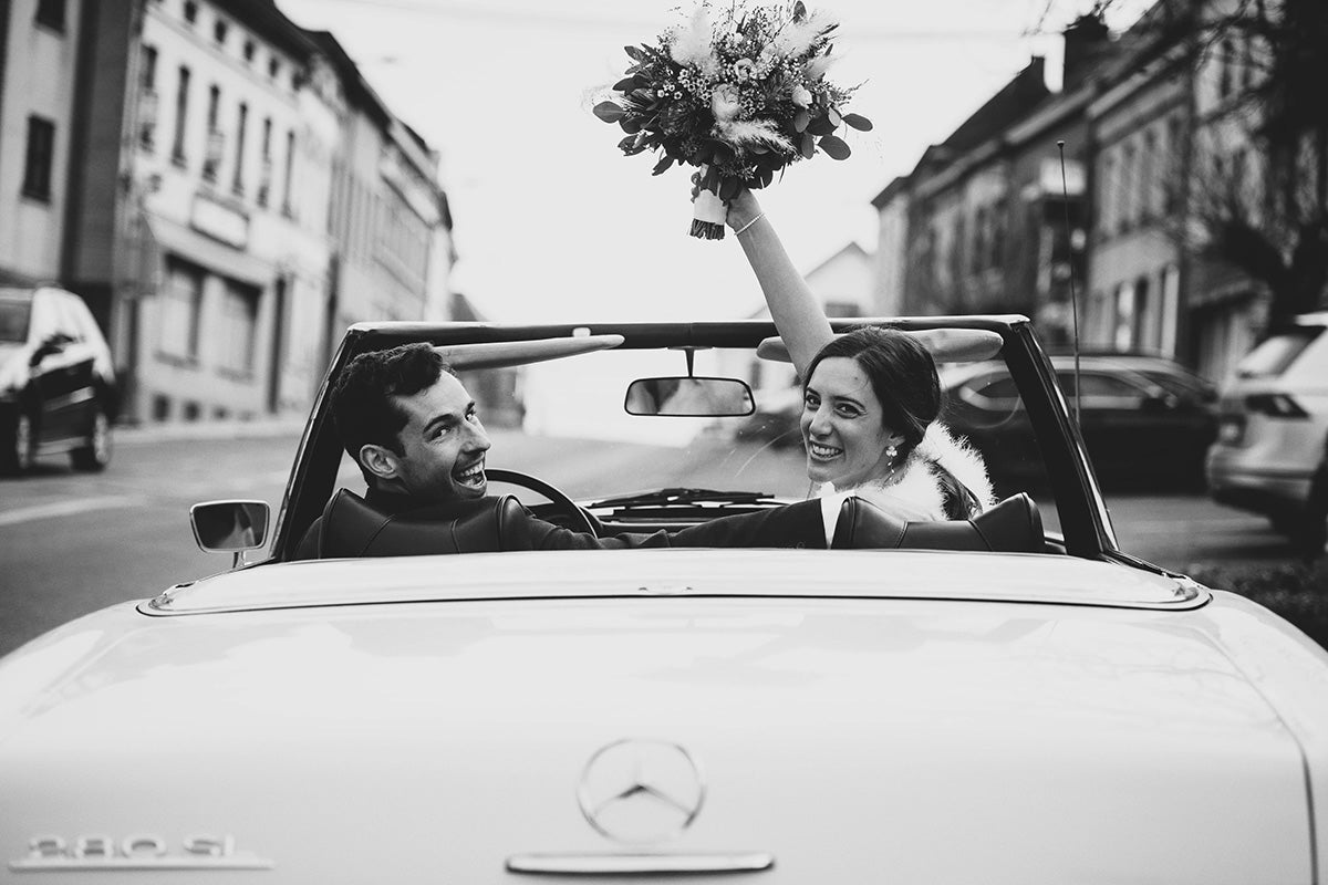 Les mariés dans leurs voiture regardant derrière eux en souriant 