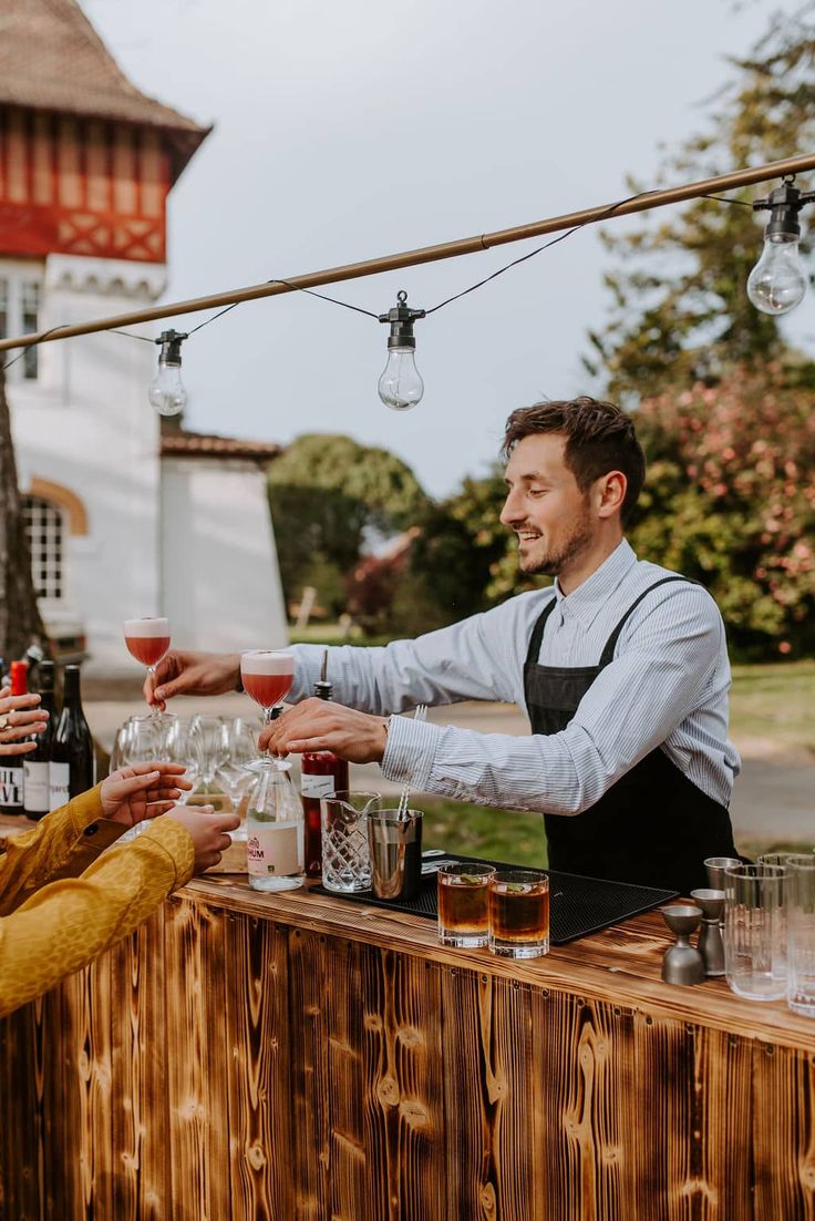 barman derrière son bar pour une animation mariage en train de servir les invités de leur cocktails