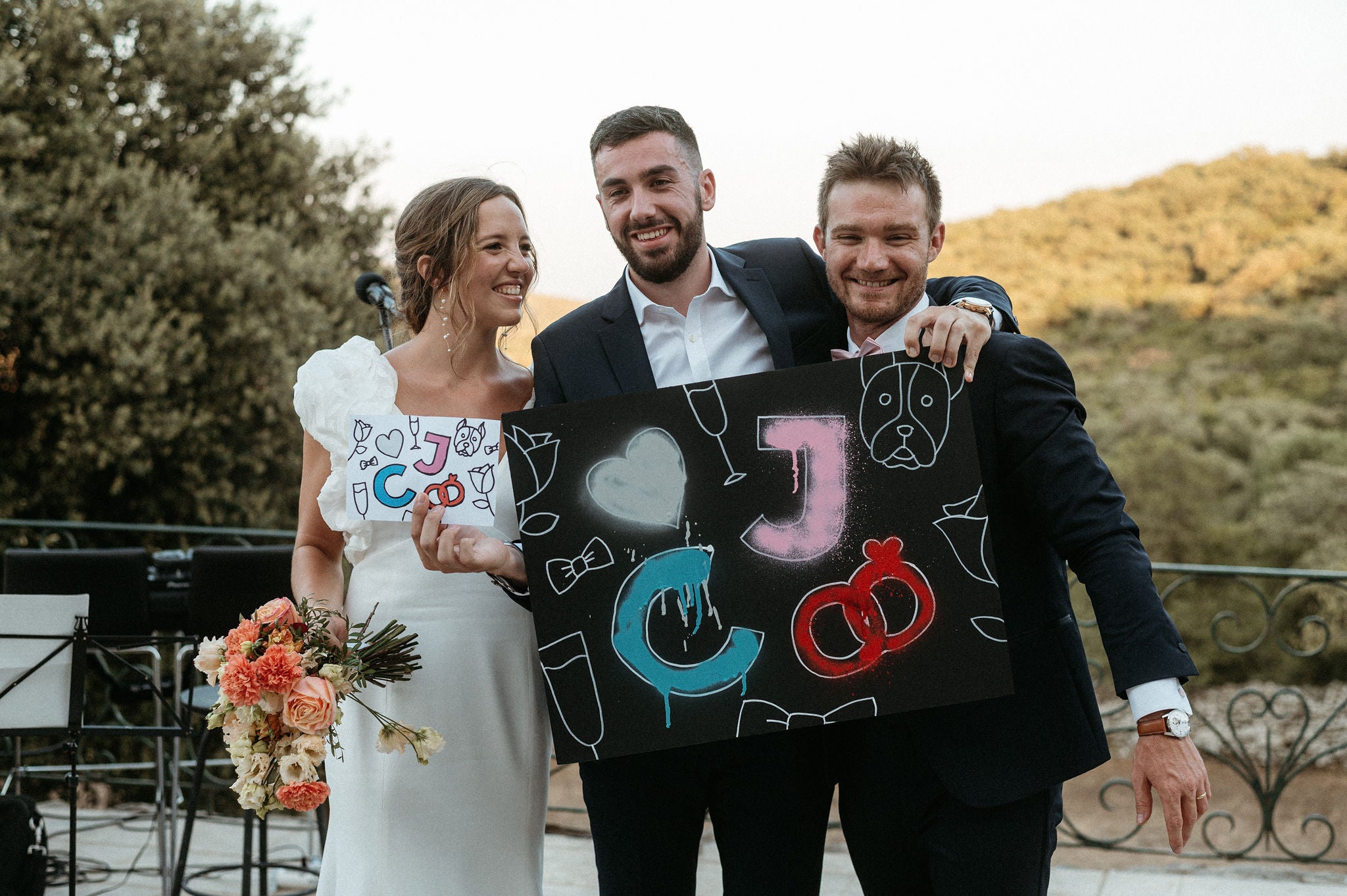 3 personnes le jour d'un mariage avec un pancarte dessinée à la main 