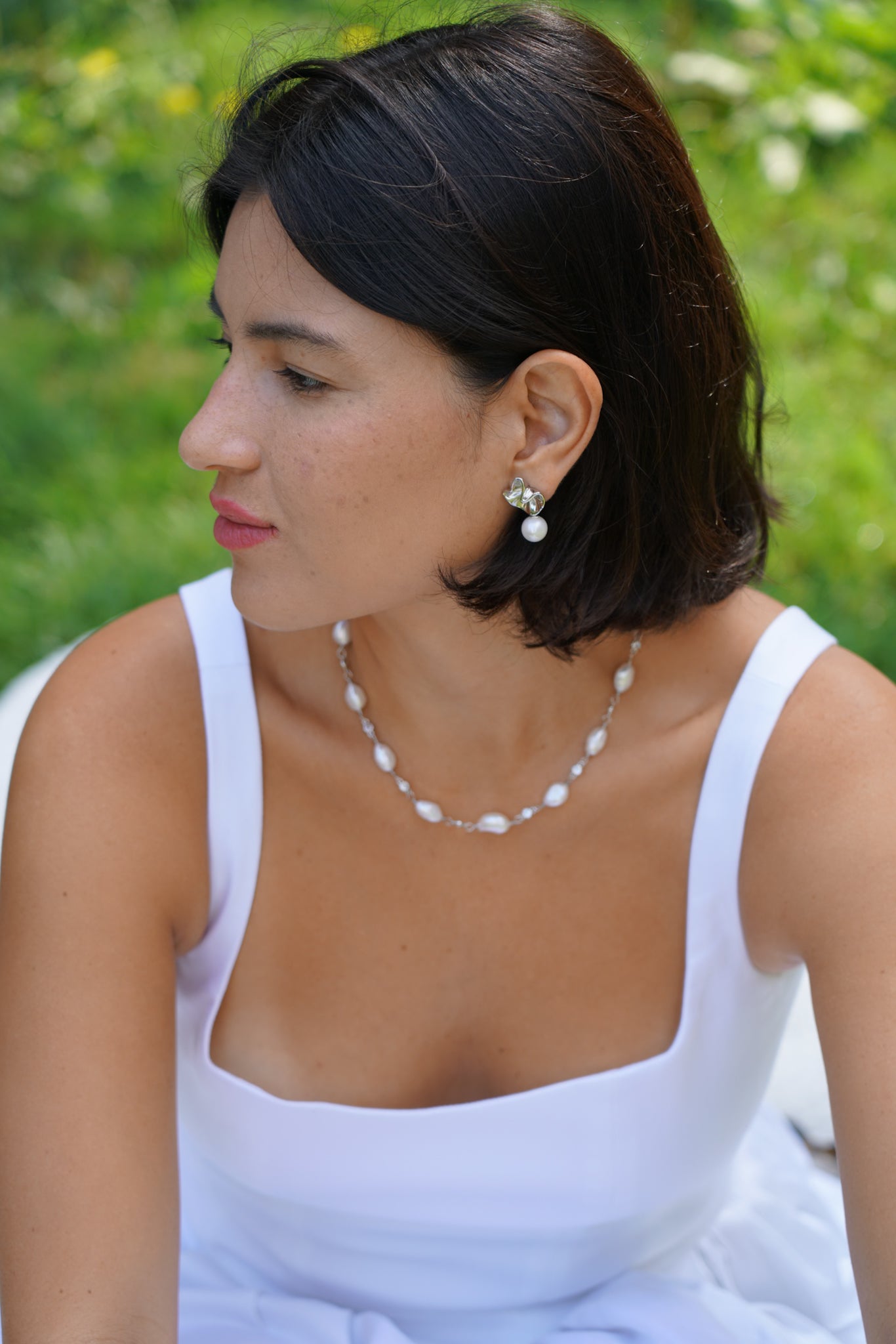 femme avec un carré portant une robe blanche et des accessoires en argent et en perles naturelles