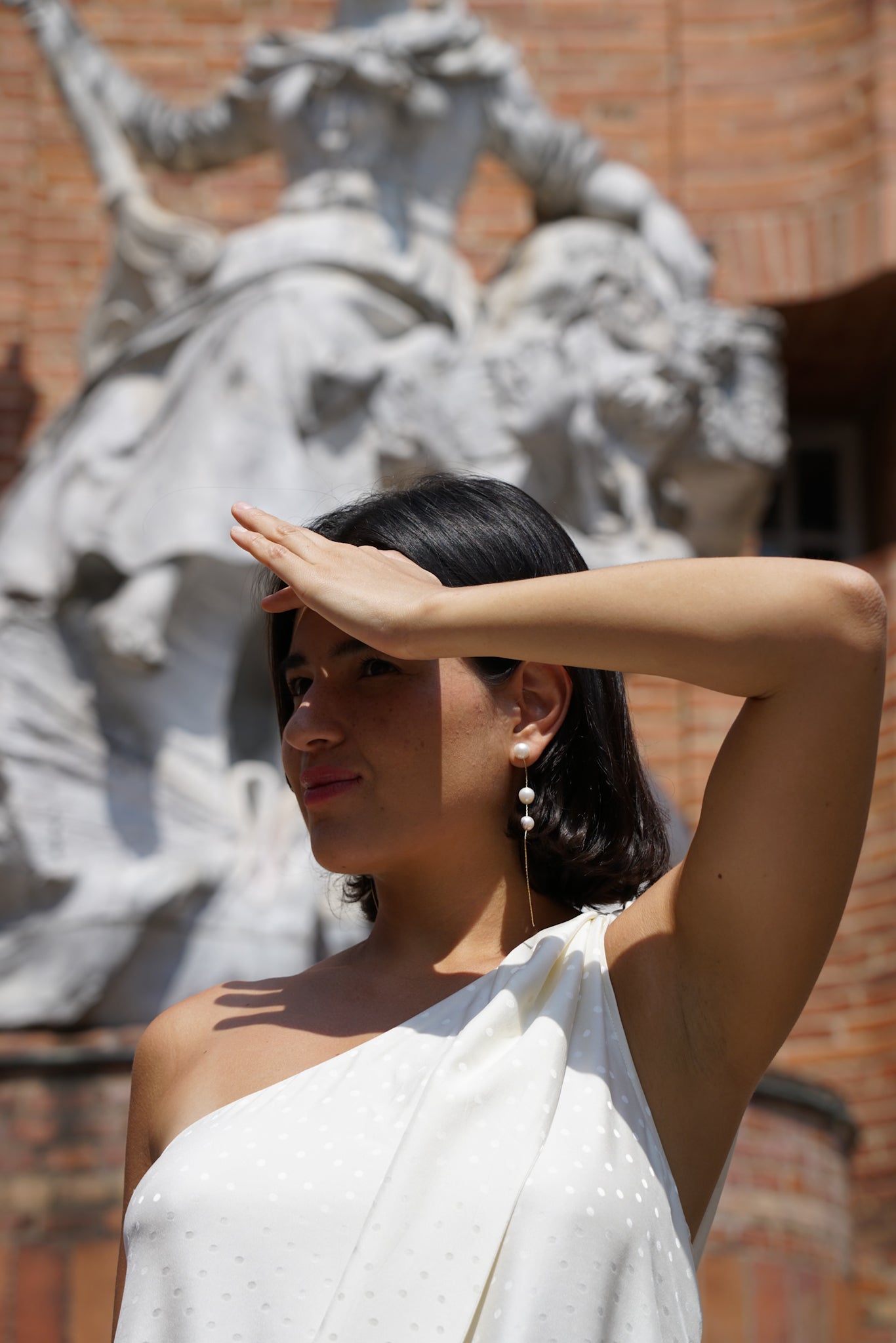 femme se cachant la tête avec la main portant des boucles d'oreilles pendantes avec des perles naturelles