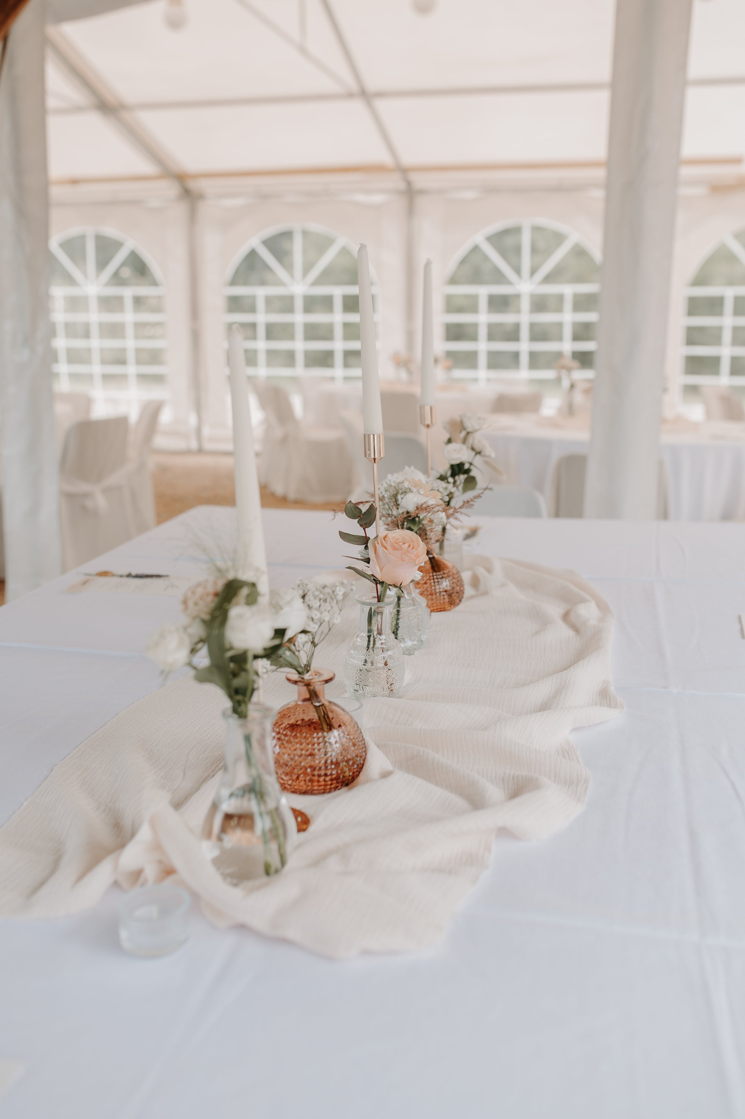 Décoration des tables pour la soirée de mariage minimaliste avec des fleurs et des bougies au centre