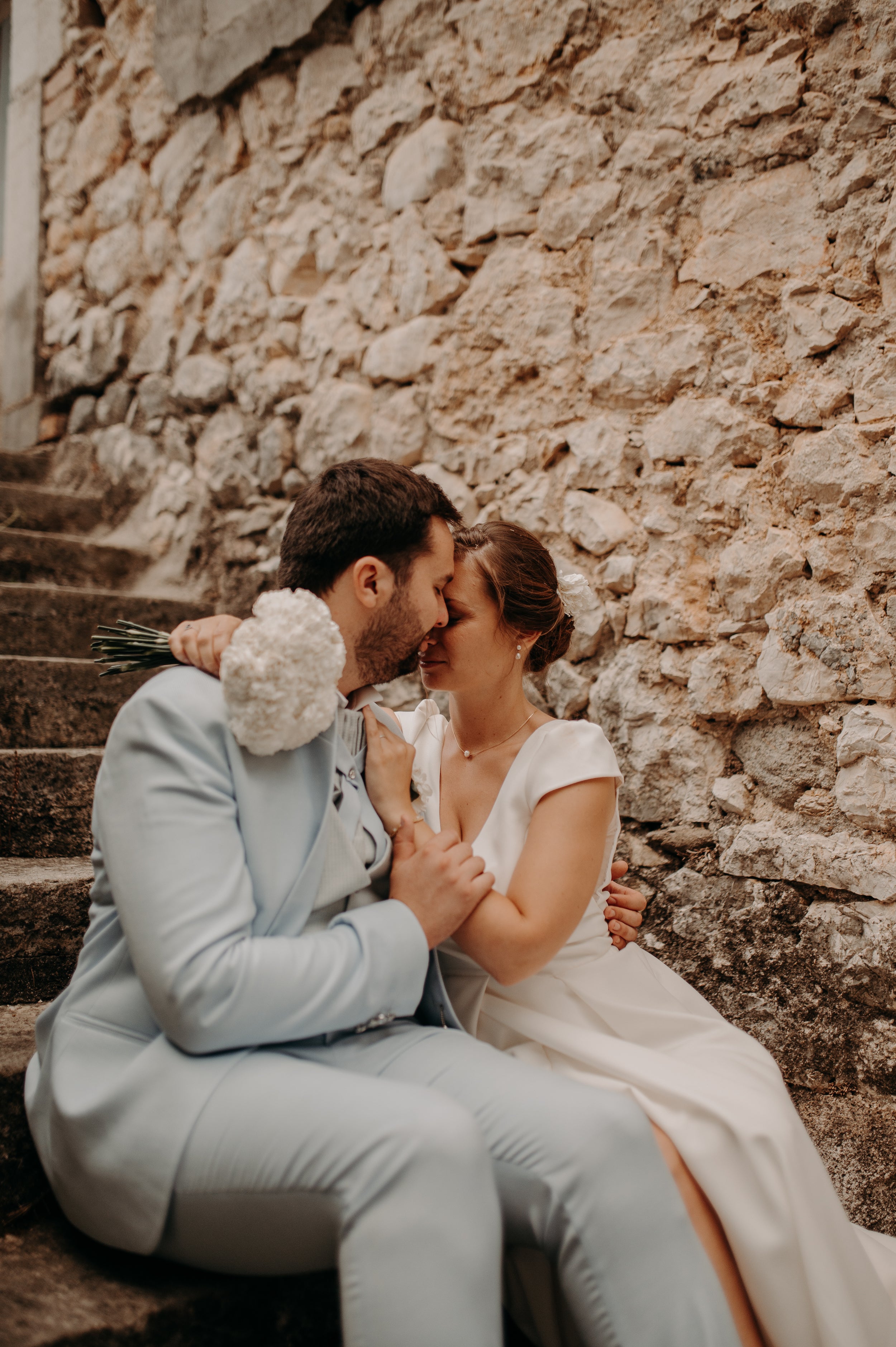 Deux amoureux tête contre tête en tenue de mariés avec des bijoux de mariage en perles