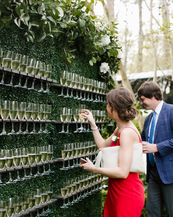 femme prenant un verre de champagne sur un mur de verre de champagne en faux gazon vert pour un animation mariage