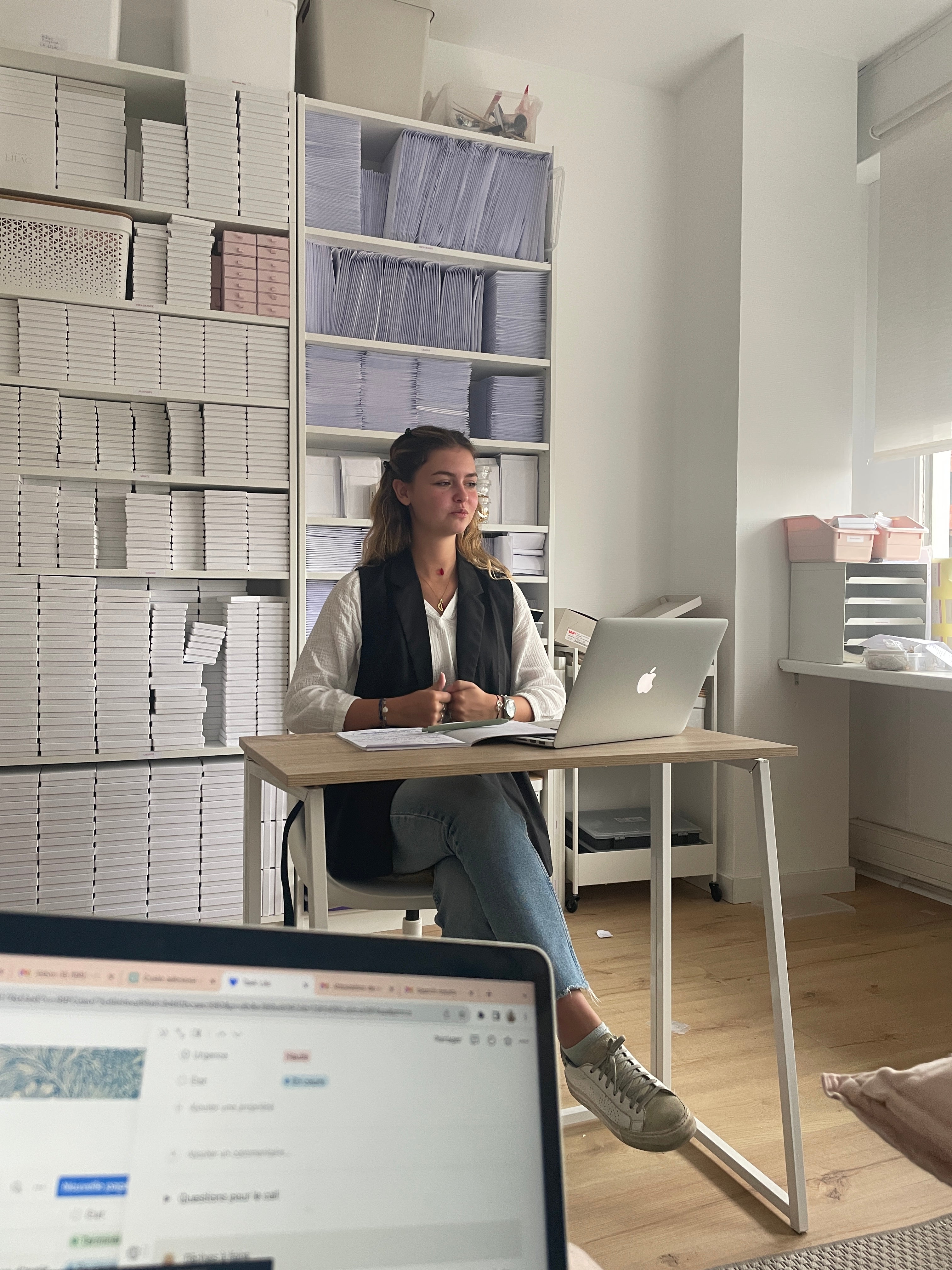 Femme qui parle lors d'une réunion dans un atelier de bijoux et accessoires pour mariées avec en arrière plan des emballages