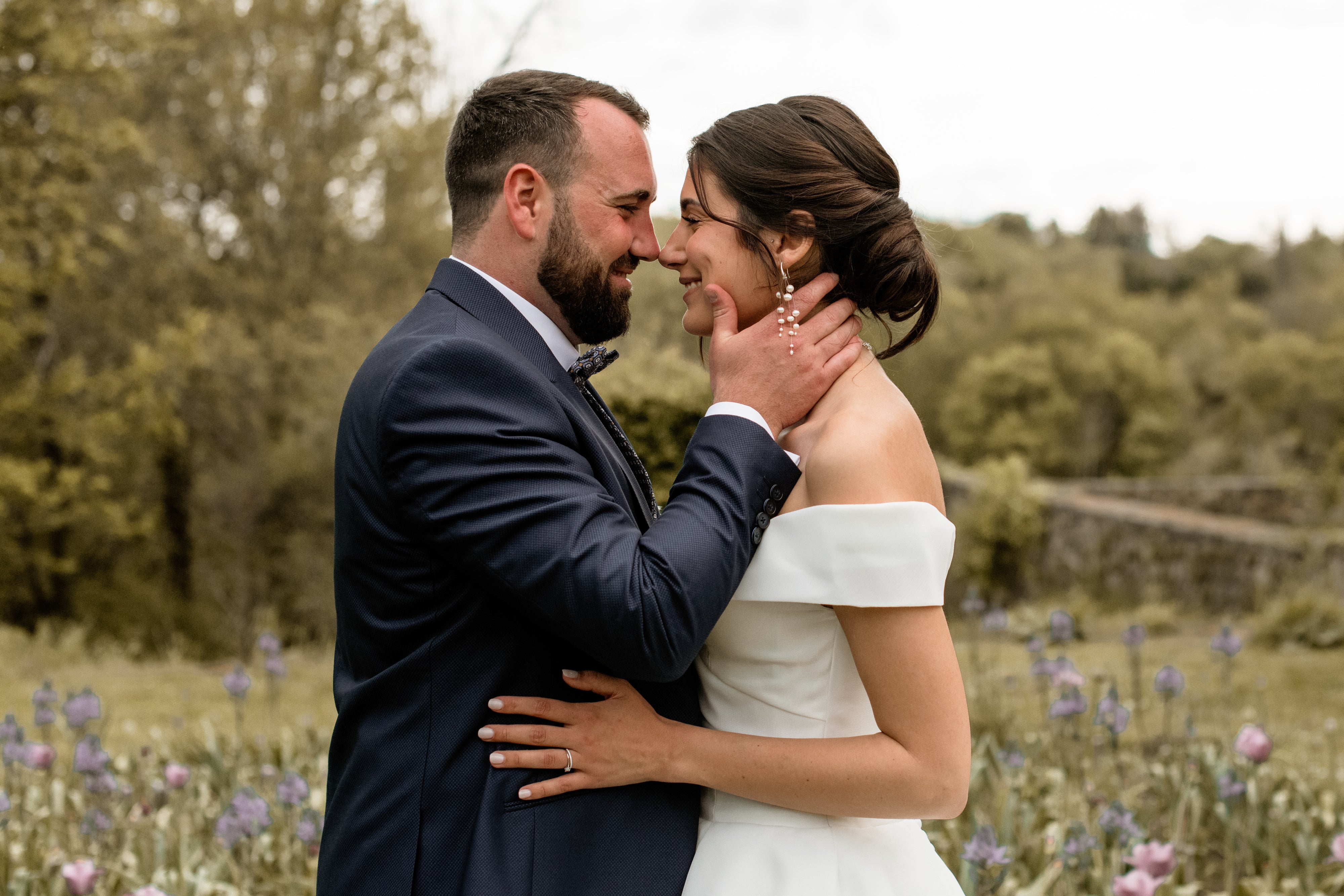 Le mari et la femme se regardant dans les yeux montrant les boucles d'oreilles de la mariée en perles naturelles asymétriques