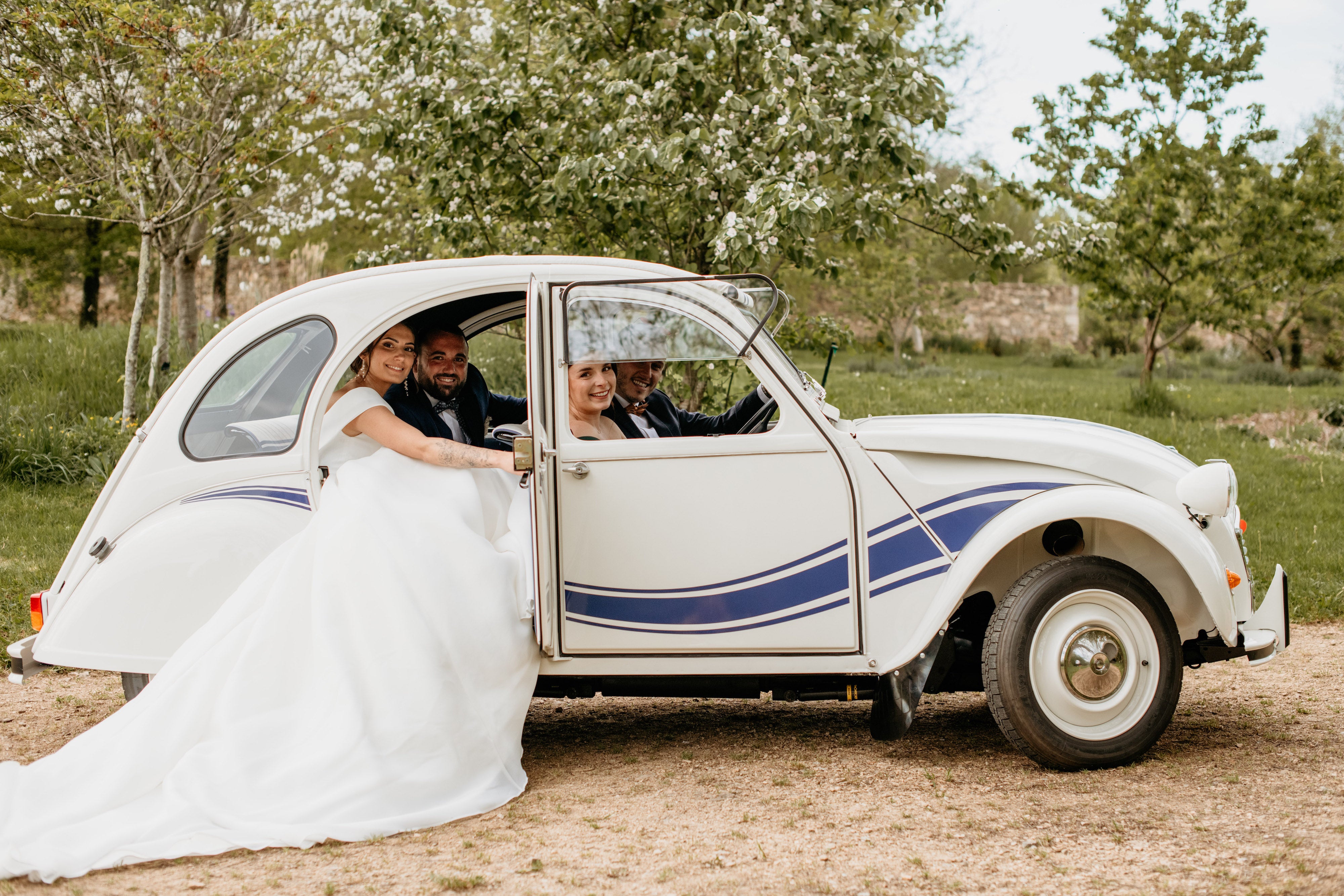 Couple de mariés dans une vieille voiture avec la robe qui dépasse