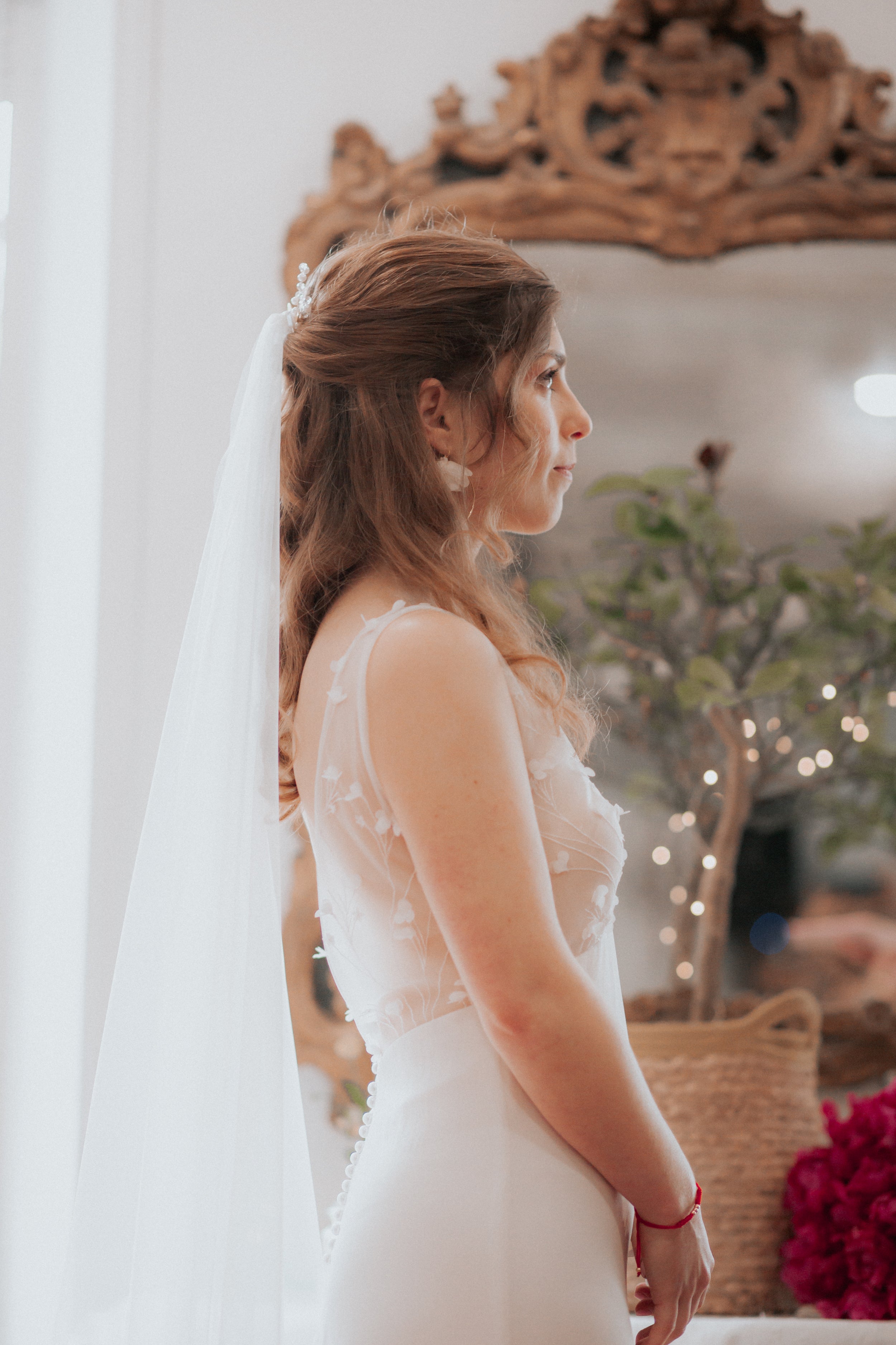 Femme de profil pendant la cérémonie de son mariage portant une tenue et des accessoires de mariage 