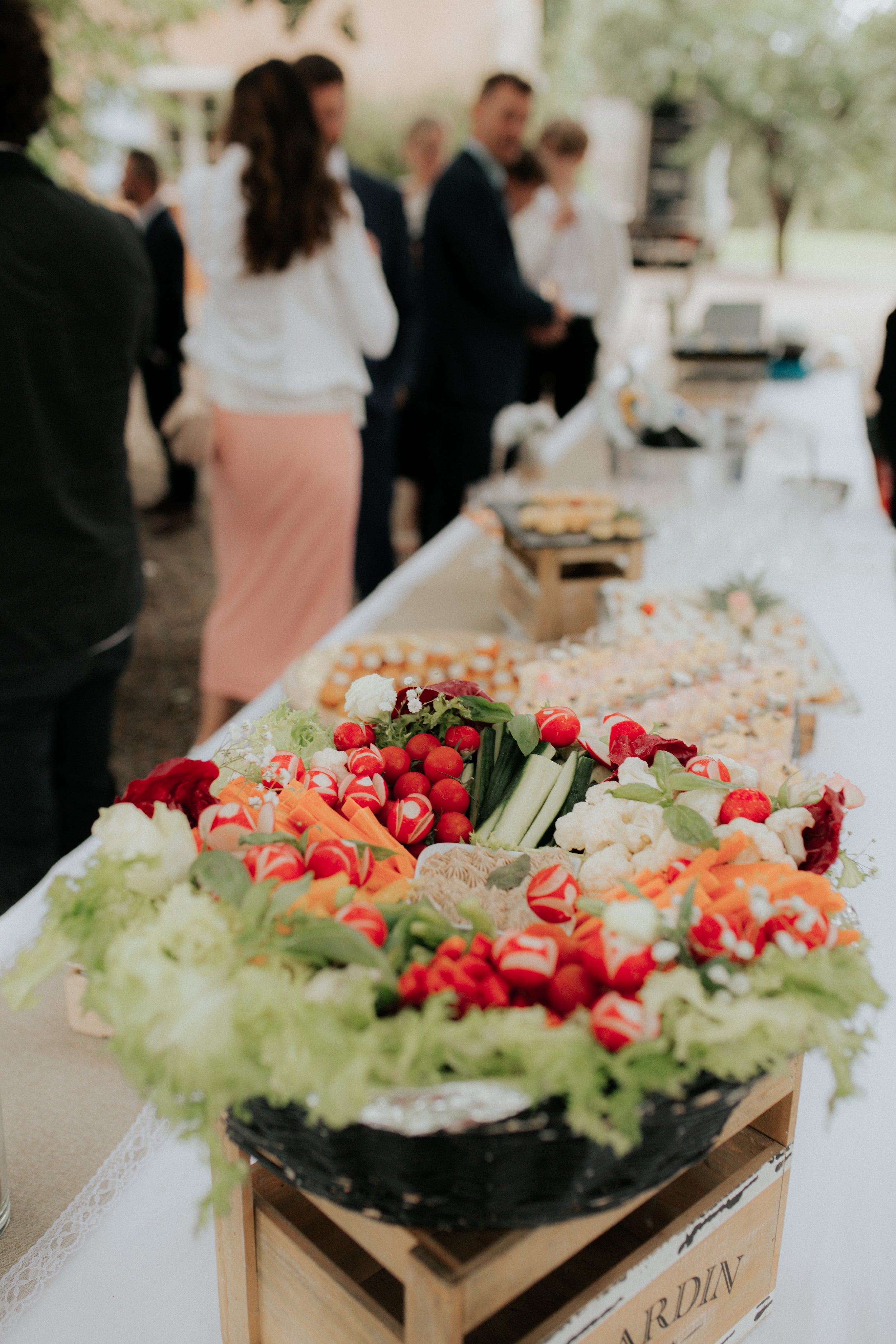 Focus sur le buffet du mariage où on peut voir des invités dans l'arrière plan