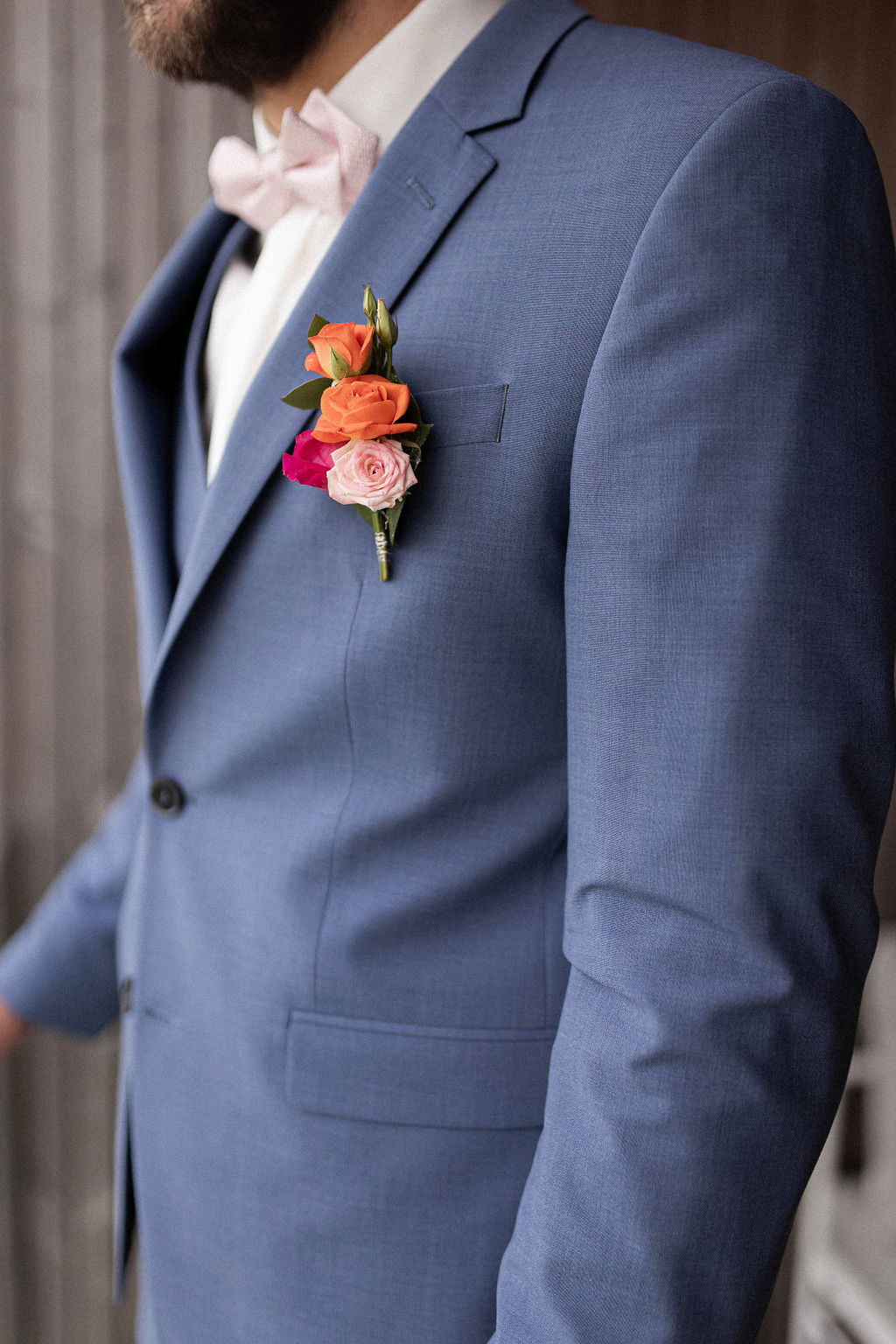 costume d'un homme marié prise de près avec la pochette de sa veste décorée avec des fleurs de couleurs