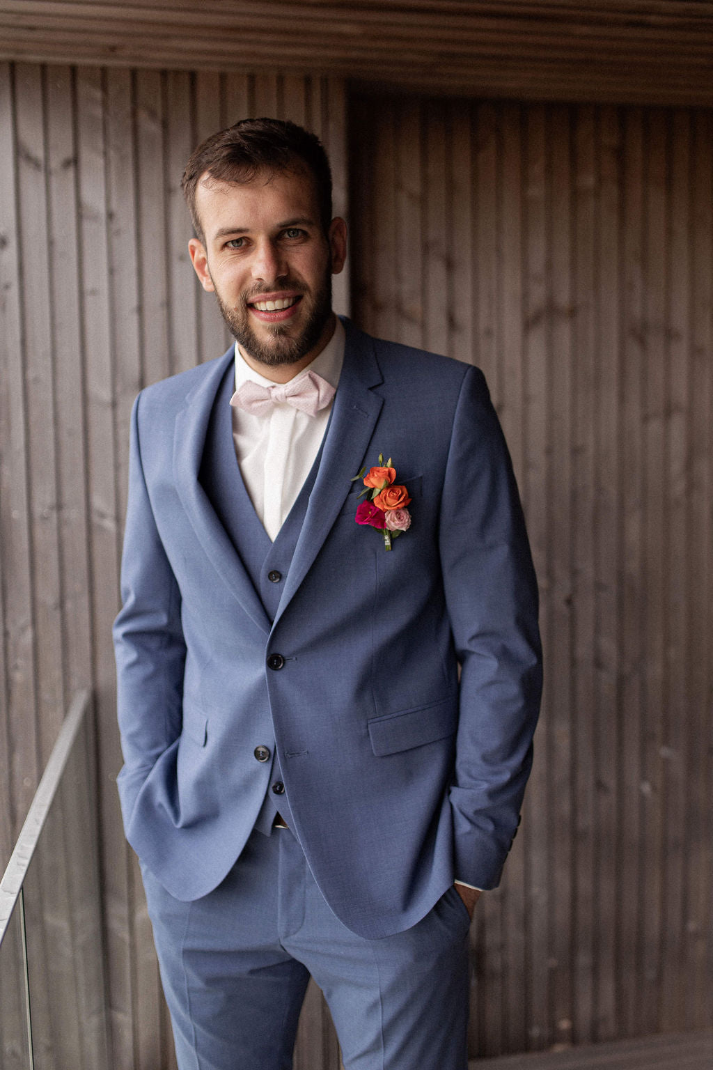 un homme en costume bleu marine et une chemise blanche, le jour de son mariage, souriant  