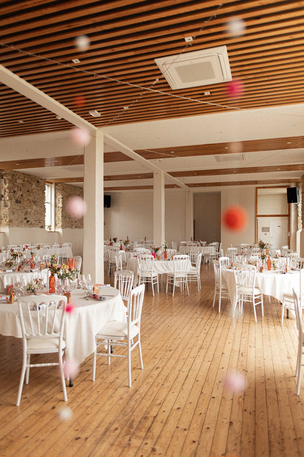 salle de mariage pour une réception avec un parquet et des tables blanches avec des fleurs sur les tables