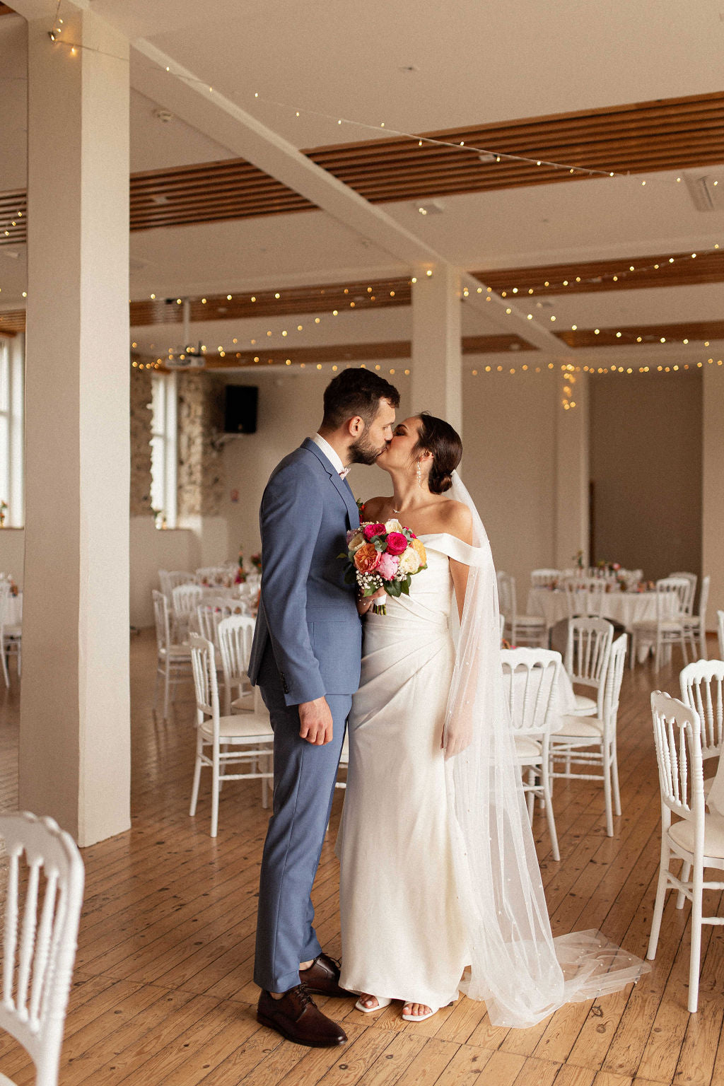 couple le jour de leur mariage entrain de s'embrasser autour des tables de la cérémonie de mairiage