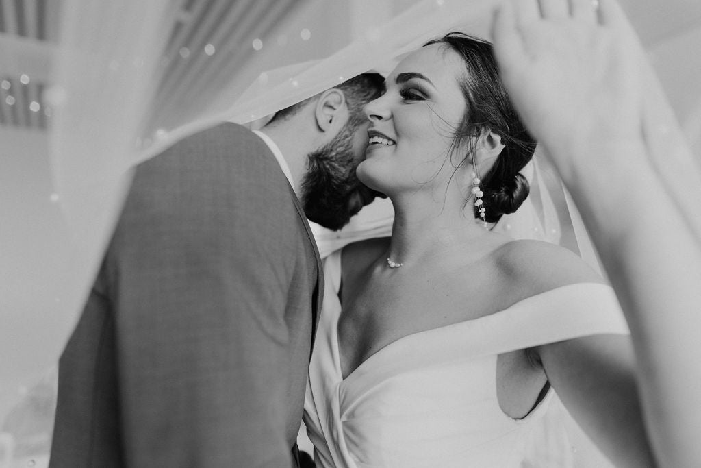 couple qui s'enlace en tenue de mariage avec un voile transparent sur la tête