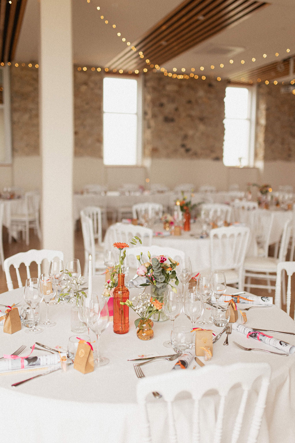 réception de mariage avec des tables et des chaises blanches et de la décoration de mariage fleurie et colorée