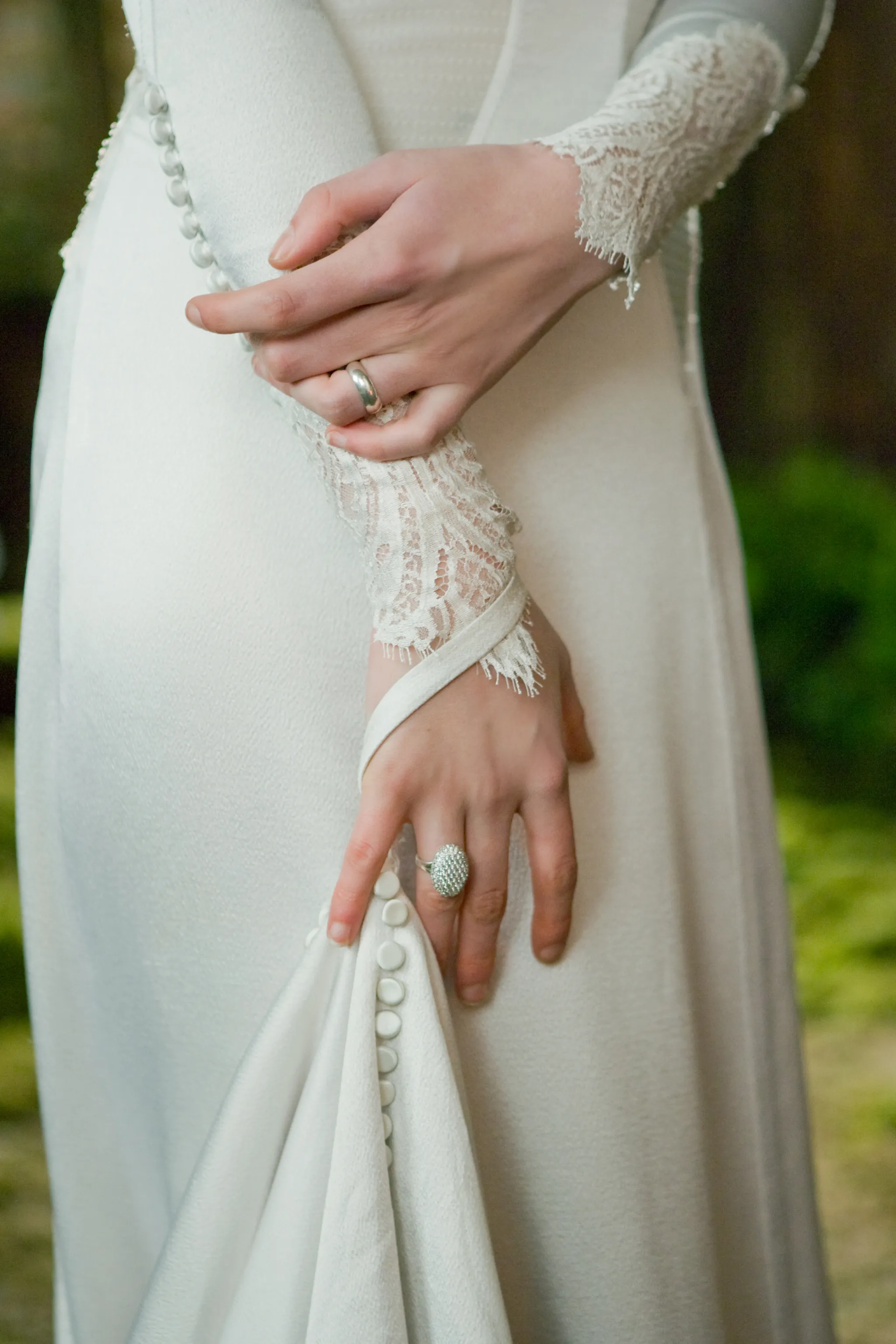 Gros plan sur les mains de Bella portant sa robe de mariée ainsi que des bijoux de mariage