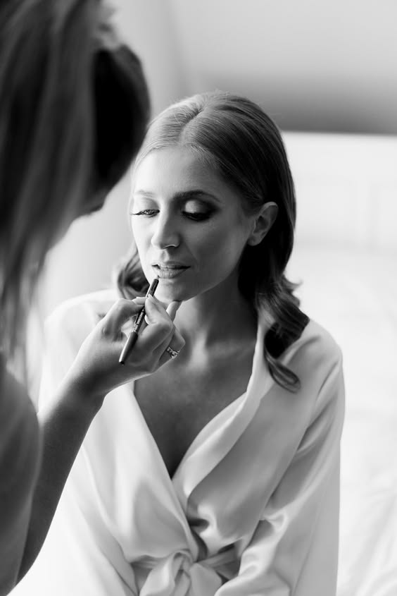 Une femme appliquant doucement son maquillage de mariage, profitant d'un moment de préparation avant le grand jour. Une étape délicate dans sa routine de beauté.