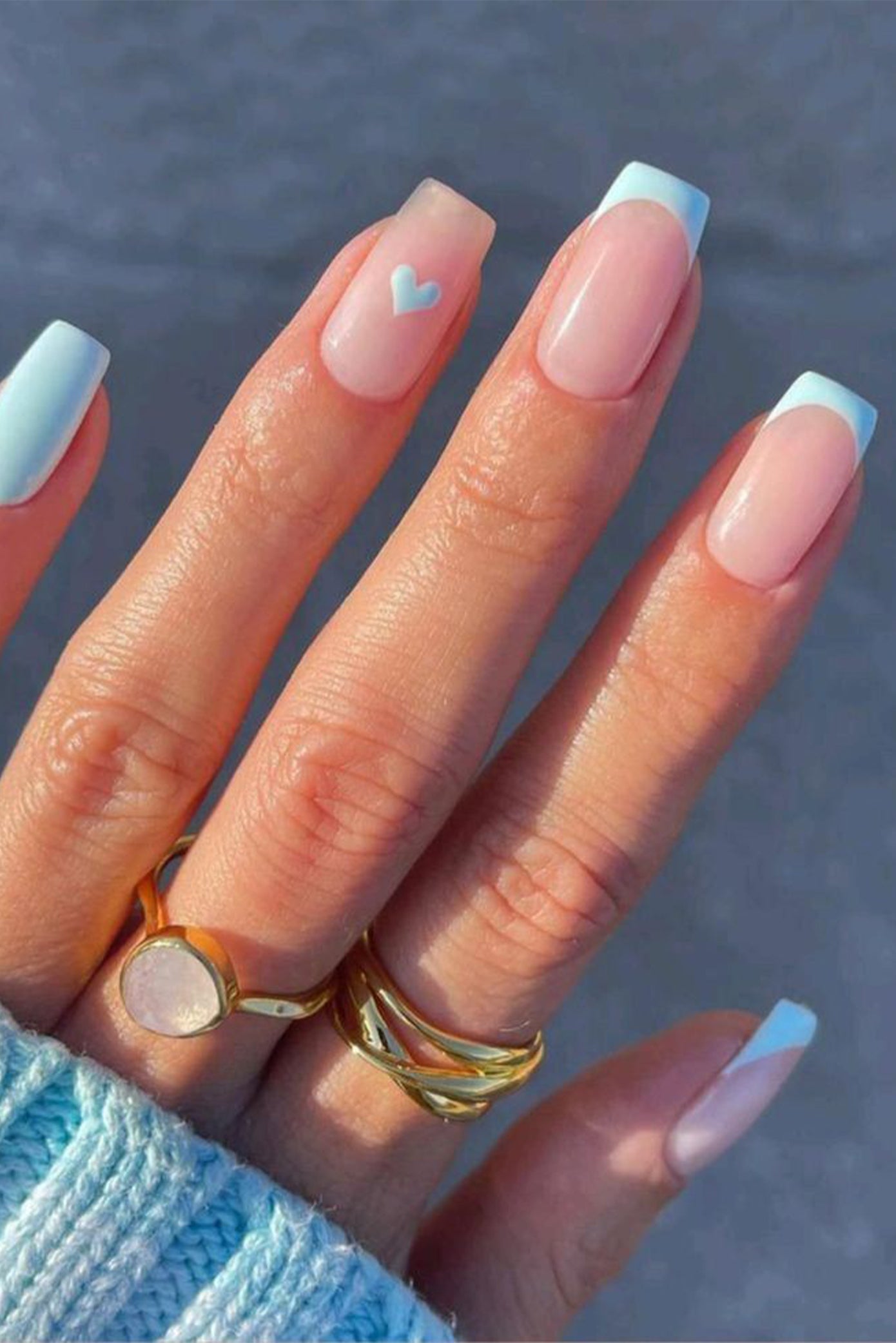 Main de mariée où on voit sa manucure style french manucure mais avec les finitions bleu et du nail art en forme de coeur sur un doigt