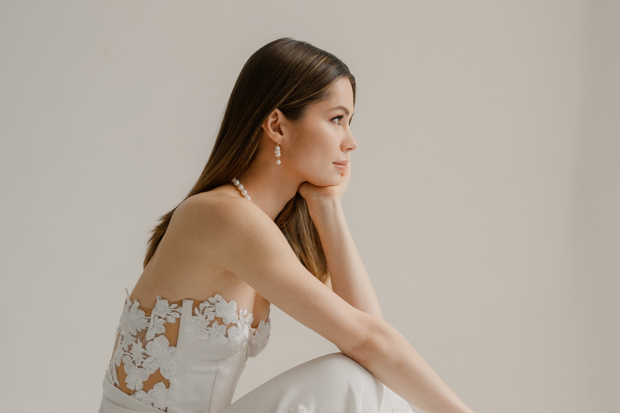 mariée portant une robe de mariage bustier avec de la dentelle et des boucles d'oreilles en perles naturelles moderne