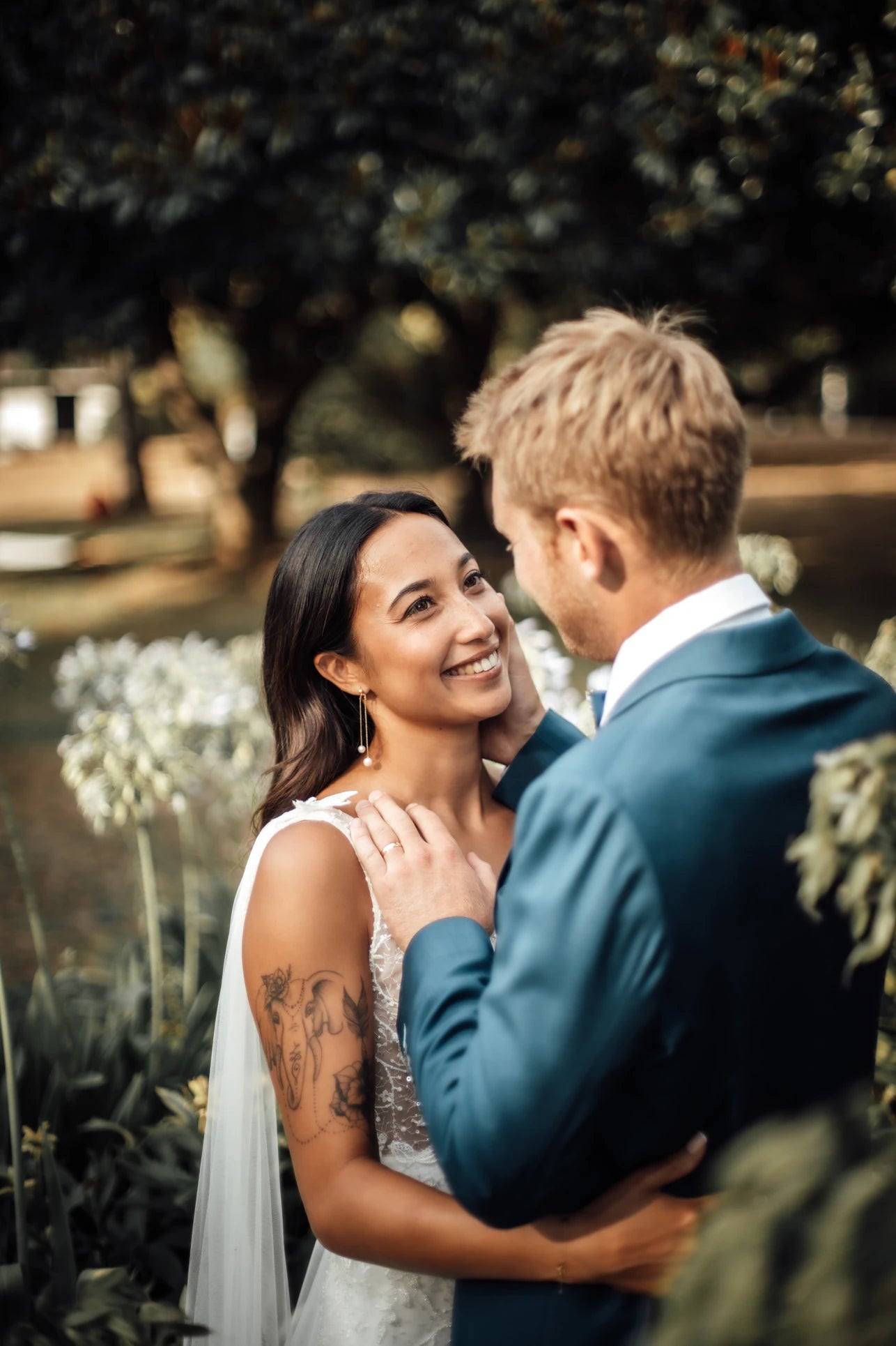 Couple de jeune mariés avec l'homme touchant la joue de sa femme avec elle qui sourit montrant ses boucles d'oreilles en perles naturelles