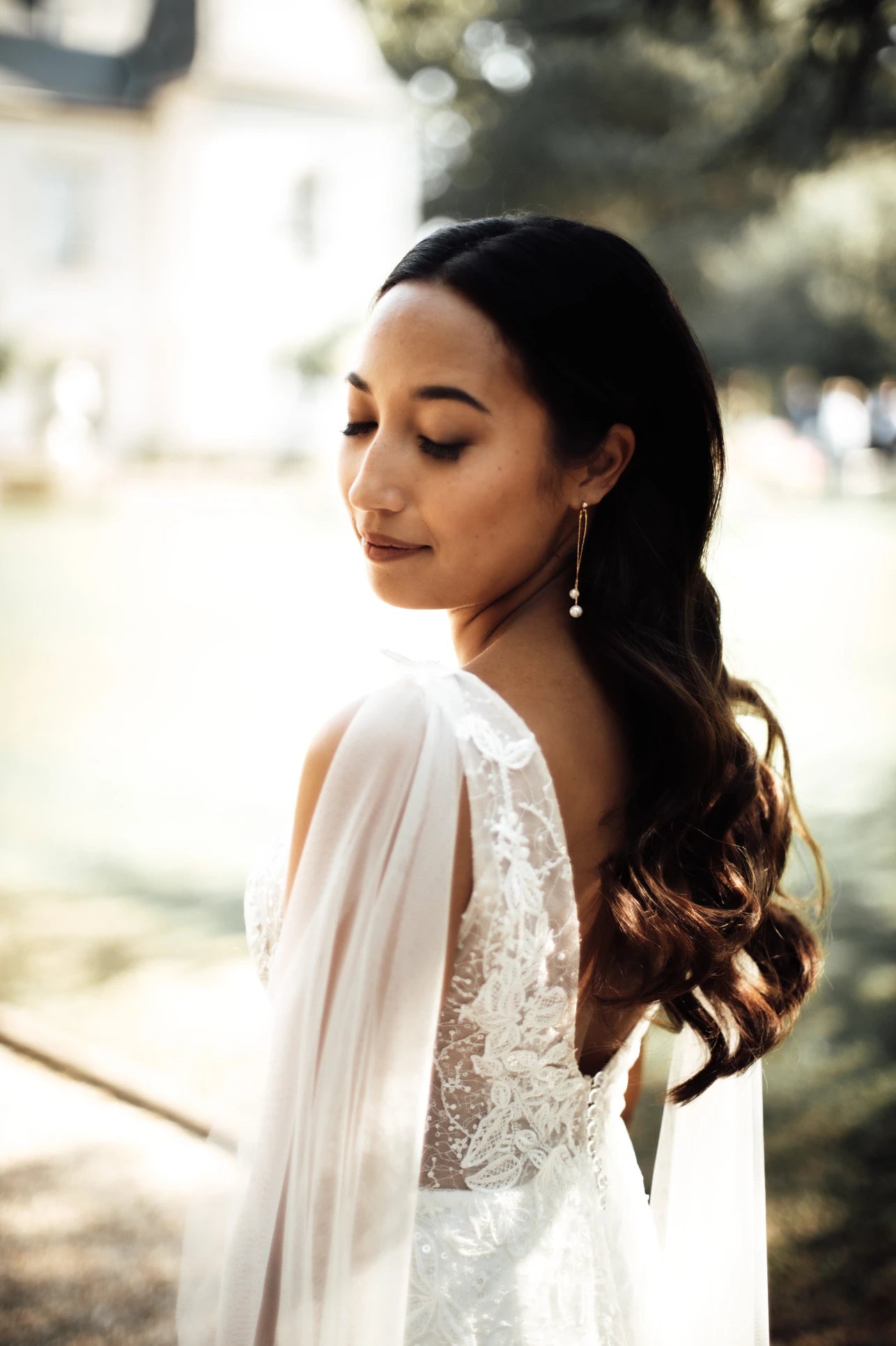 Femme avec les yeux fermés montrant sa robe de mariée et ces accessoires de mariage