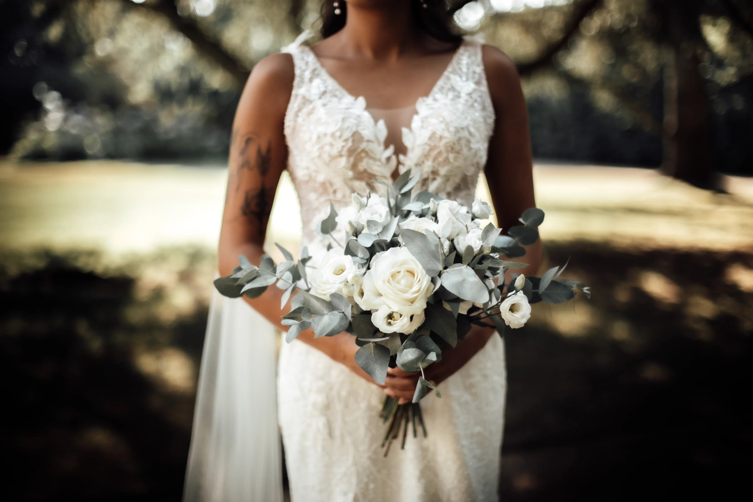 Photo mettant en avant le bouquet de la mariée permettant de voir en second plan la robe raffinée de mariage de la femme