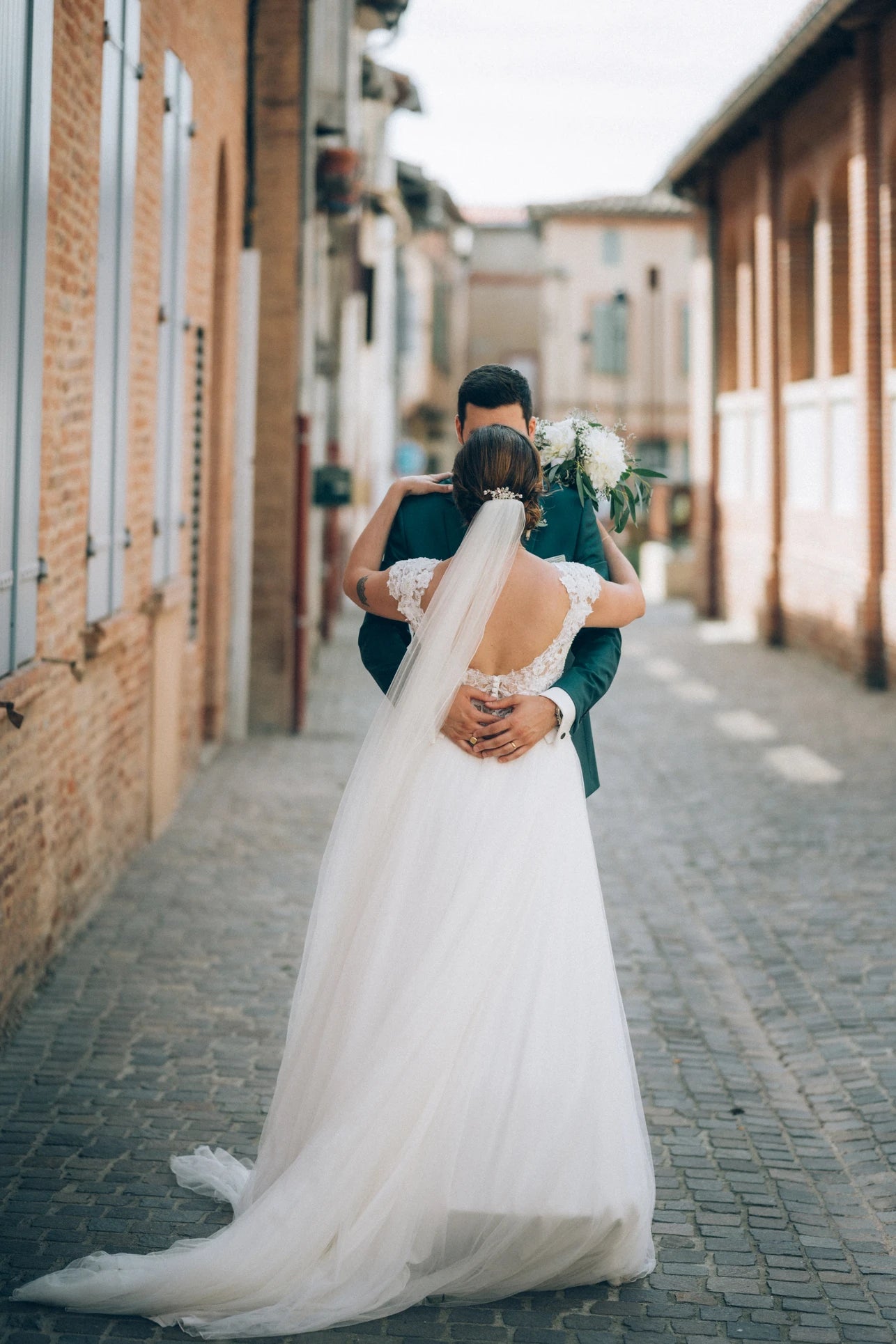 Mariée de dos enlacent son mari dans sa robe de mariage et ses accessoires de cérémonie