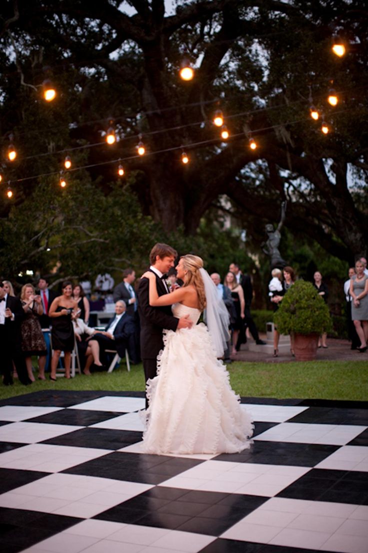 couple qui danse pour leur ouverture de bal sur une piste en damier noir et blanche