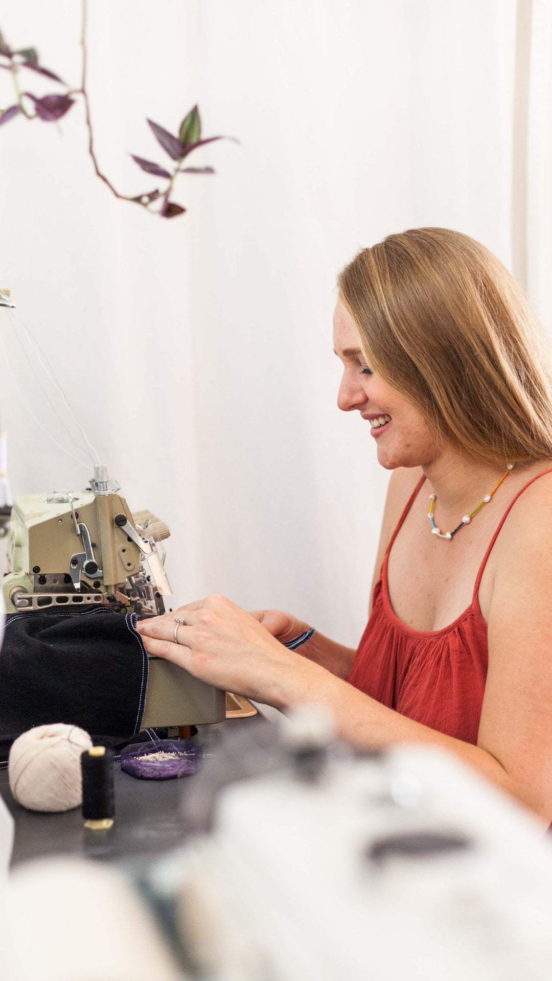 Femme souriante qui coût un vêtement de mariage avec sa machine à coudre