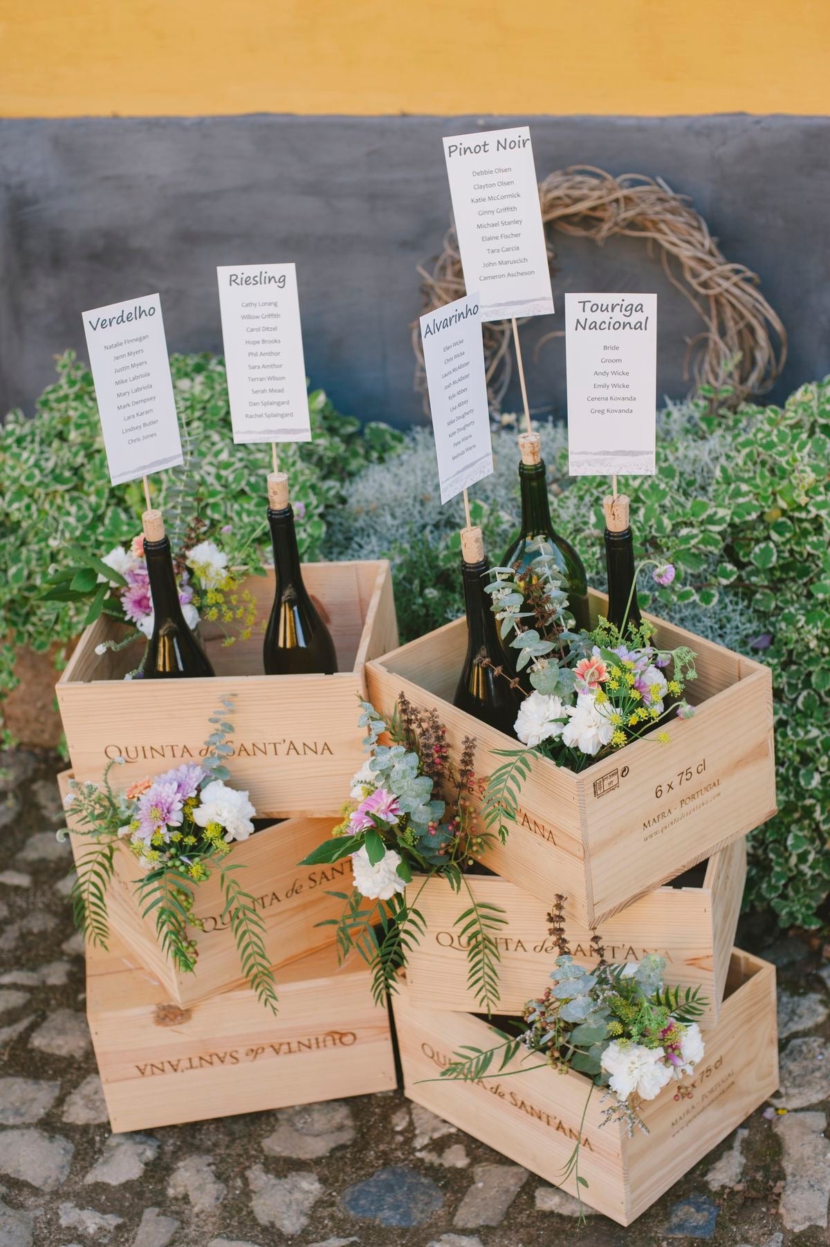 caisse en bois avec des bouteilles de vins et des fleurs à l'interieur sur un sol en pierre