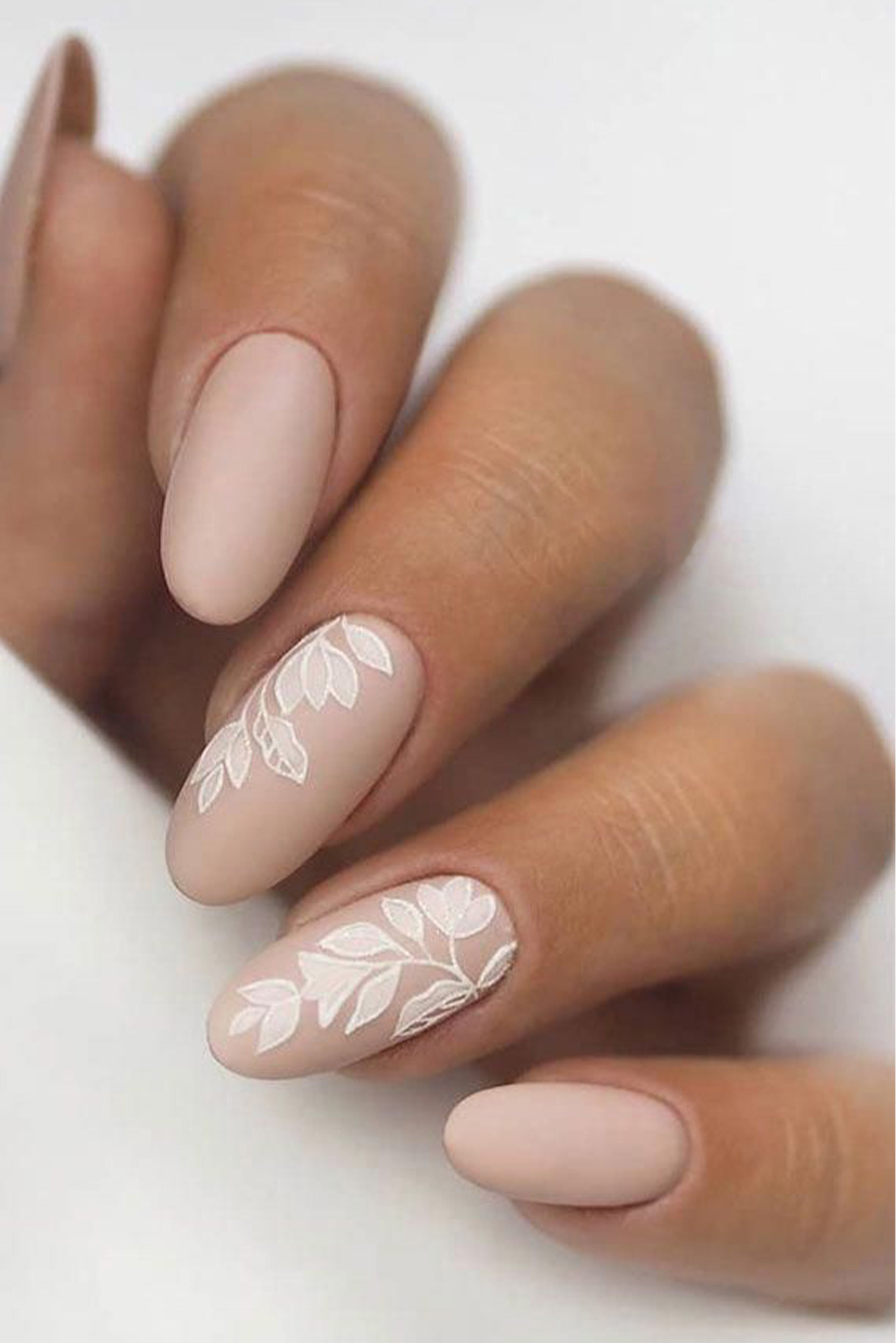 Image d'une main montrant ses ongles de mariage avec une manucure nude et un design style dentelle