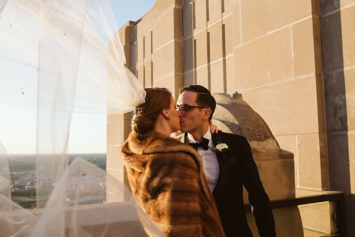 Une mariée d'hiver qui embrasse sont mari avec le voile au vent