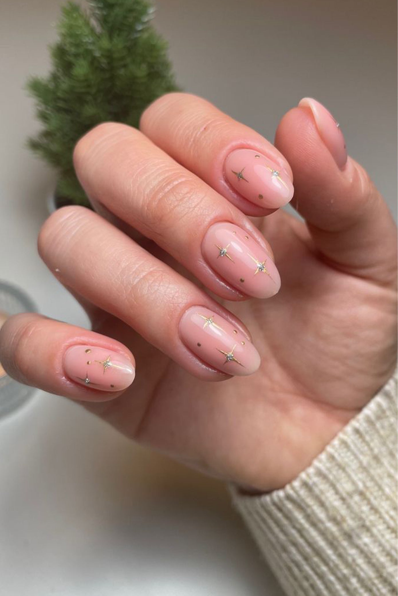 Ongle naturel en forme amande avec un vernis nude et du nail art avec des dessins d'étoiles