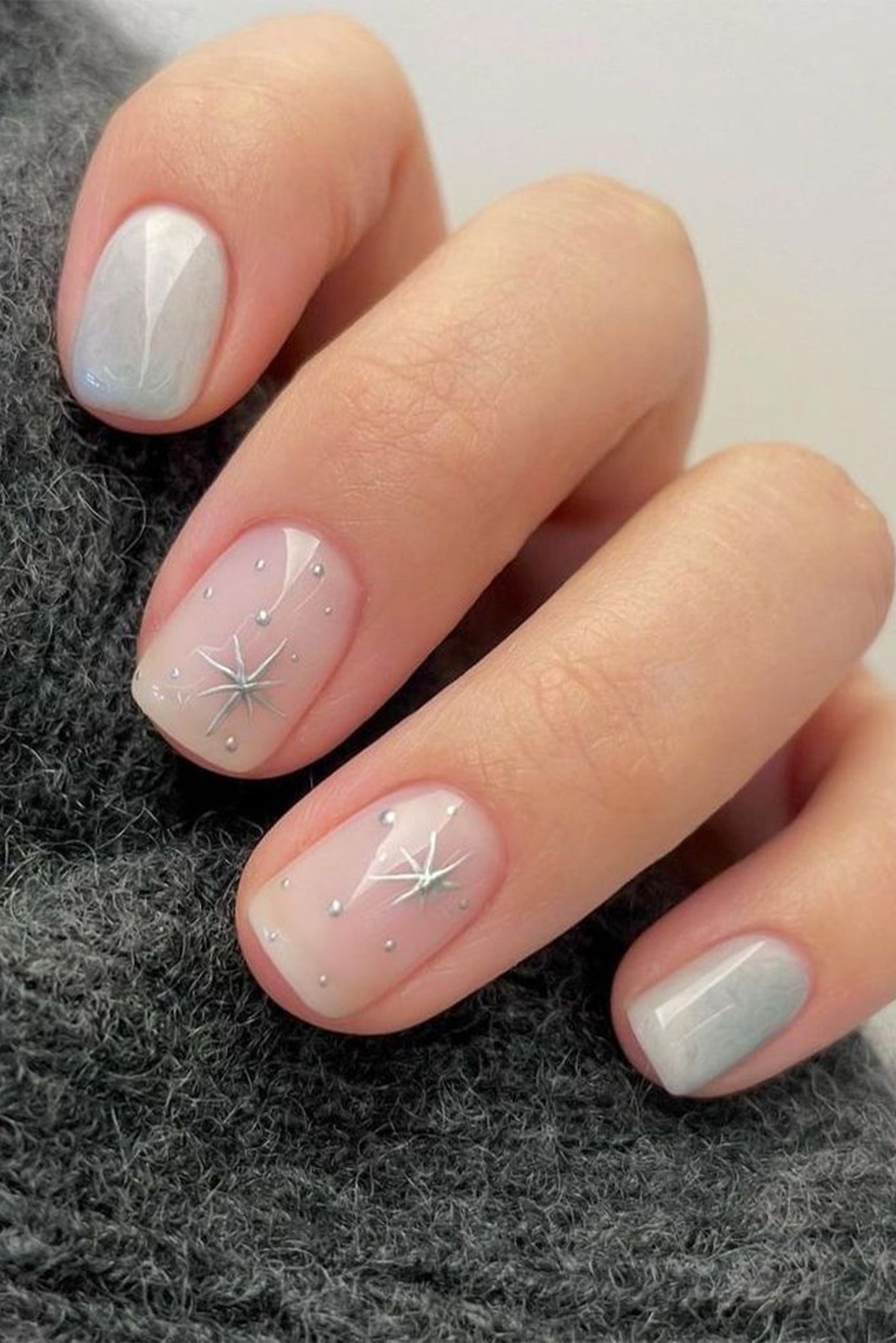 Manucure courte en forme carrée avec des ongles couleurs nude et d'autre argenté et une touche de nail art avec des étoiles sur certains doigts