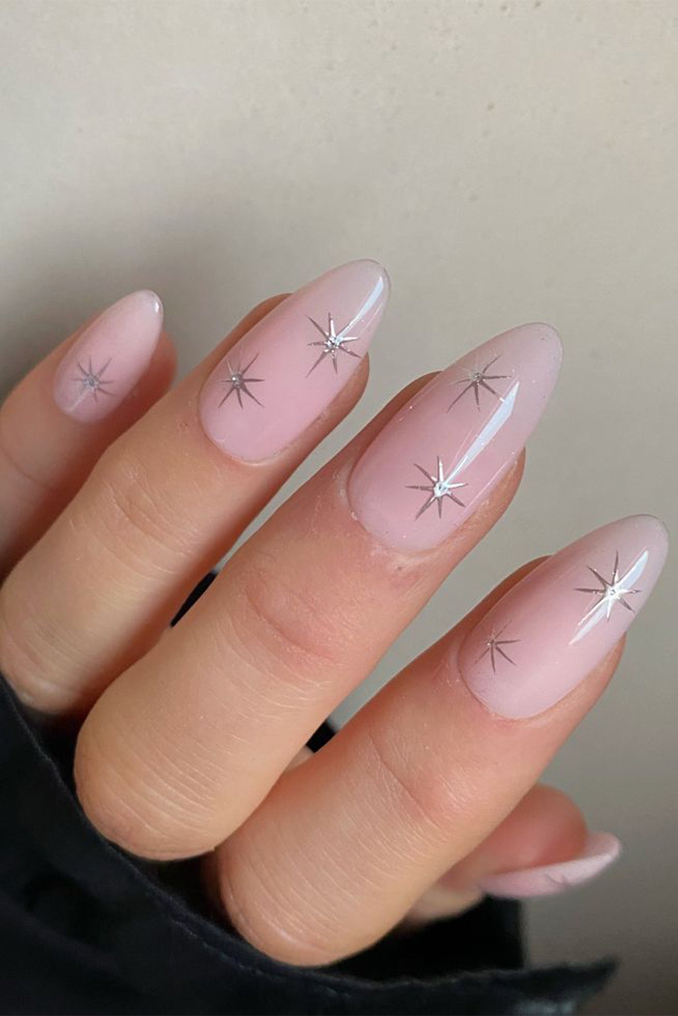 Focus sur une main de mariée avec des ongles long et une manucure naturelle comportant du nail art en forme d'étoiles 