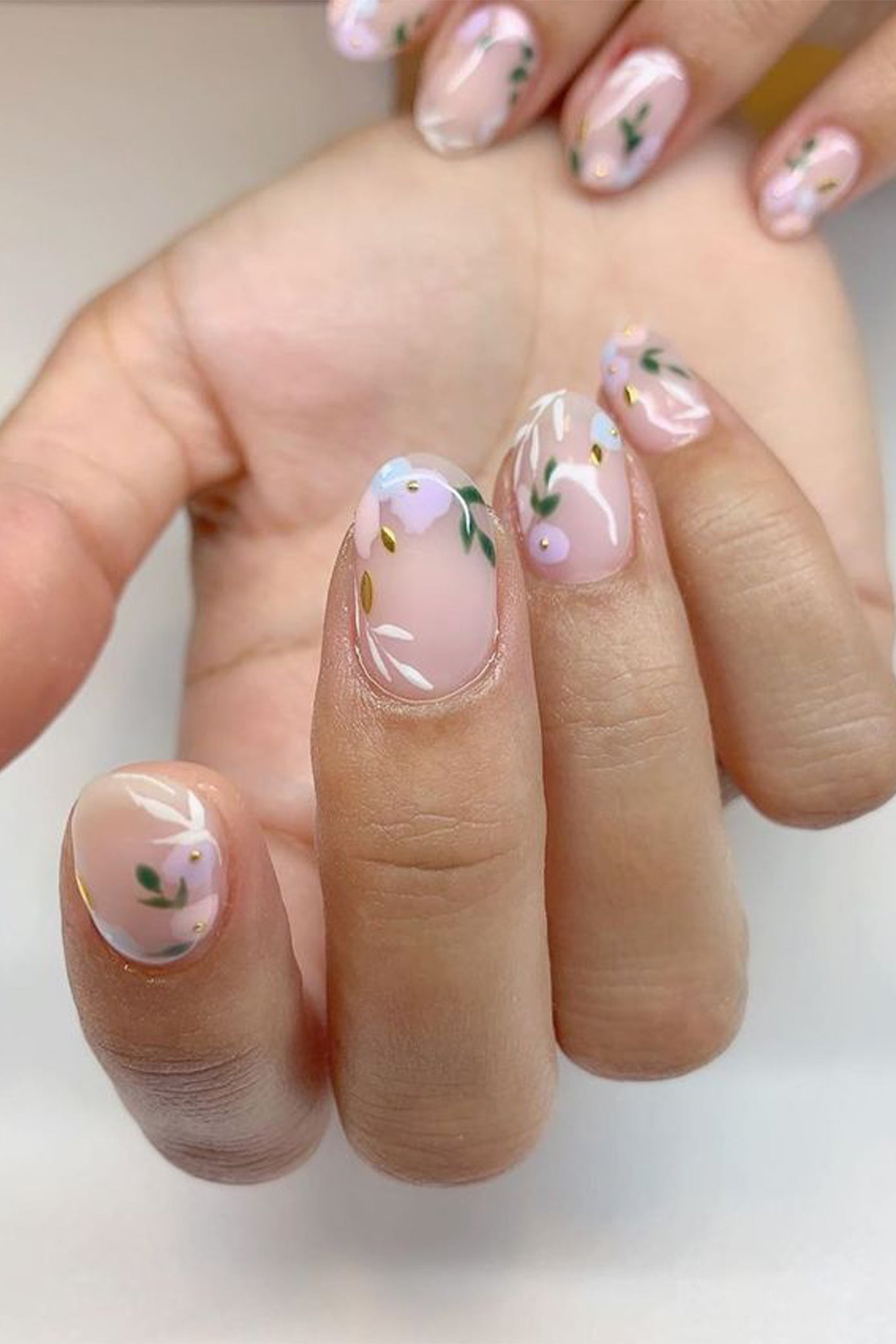 Nail art pour mariée avec des dessins de fleur sur une base de vernis nude