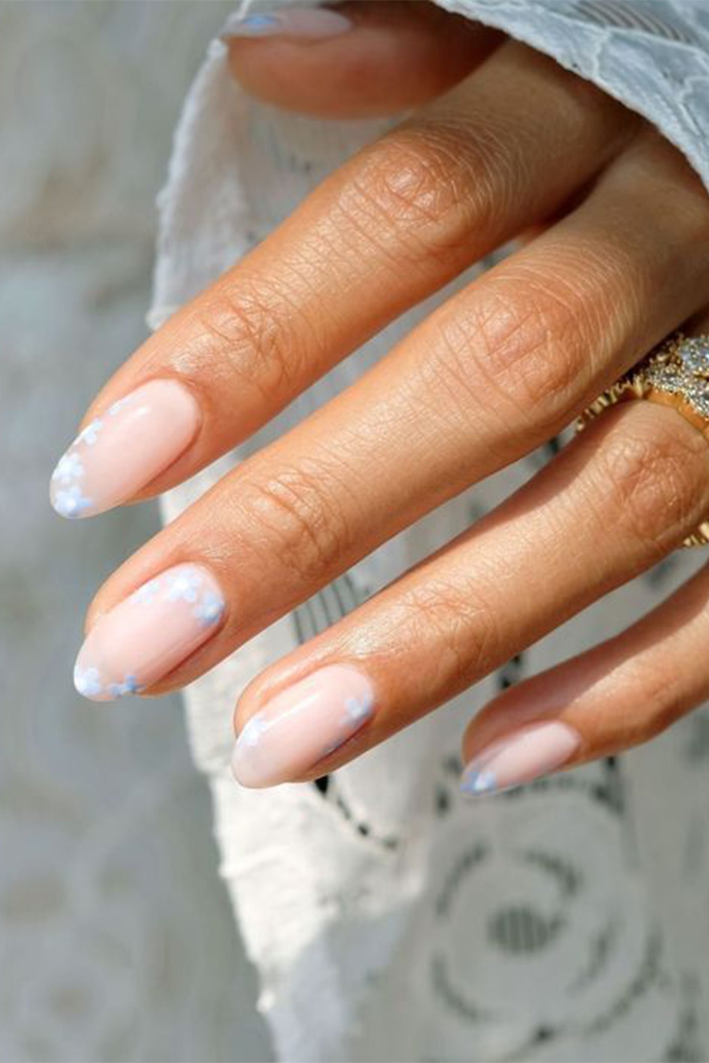 Focus sur les mains d'une mariées avec une manucure nude et du nail art style fleur de couleur bleu