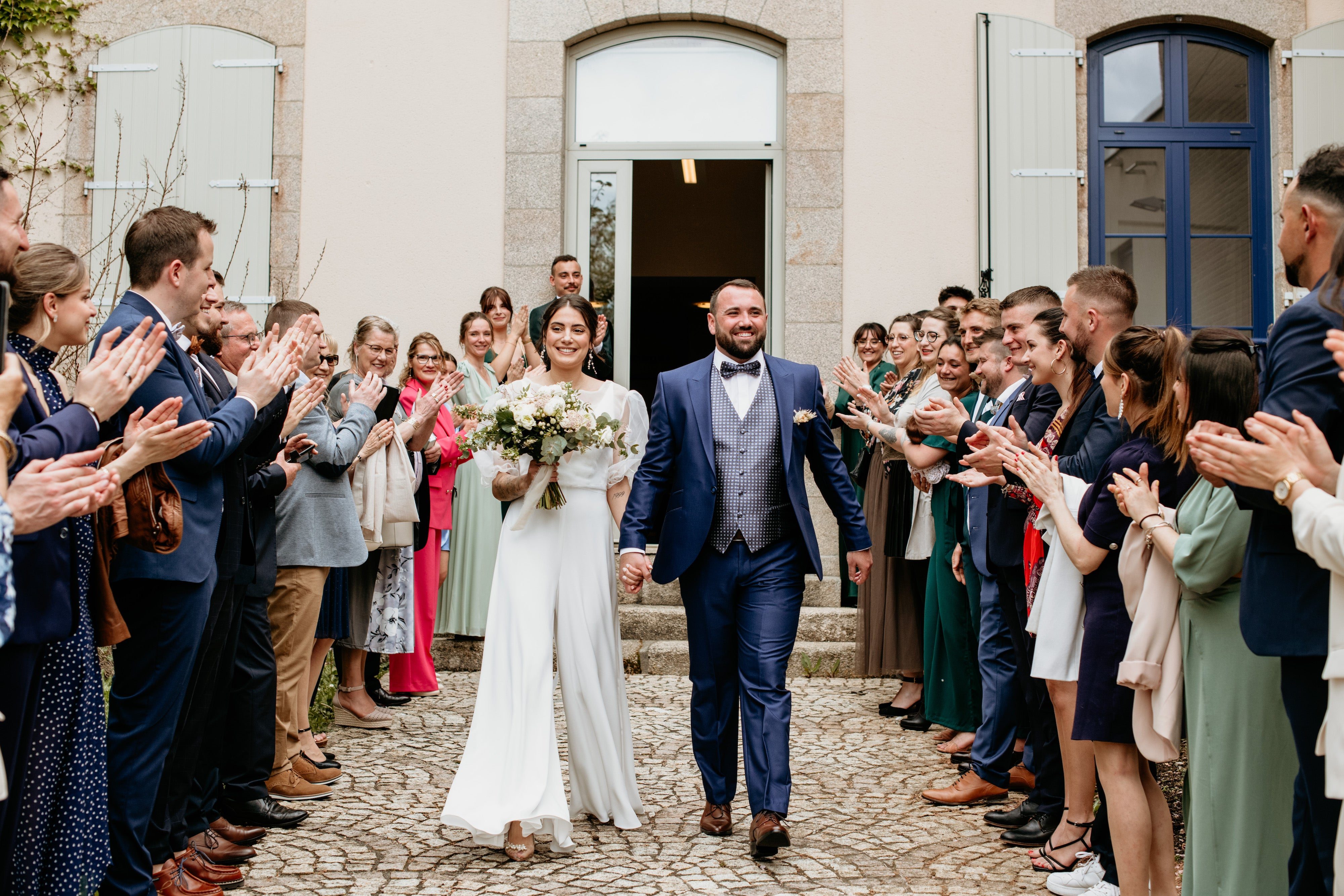 Les mariés sortant de la salle de réception en portant une tenue et des accessoires de mariage