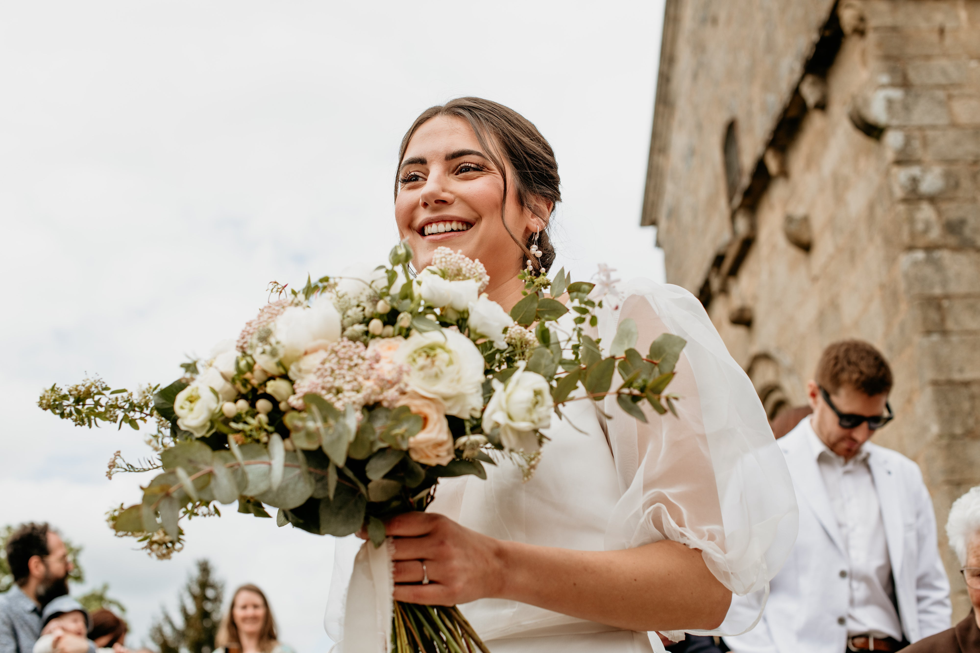 La mariée souriante portant dans sa main son bouquet de fleur 