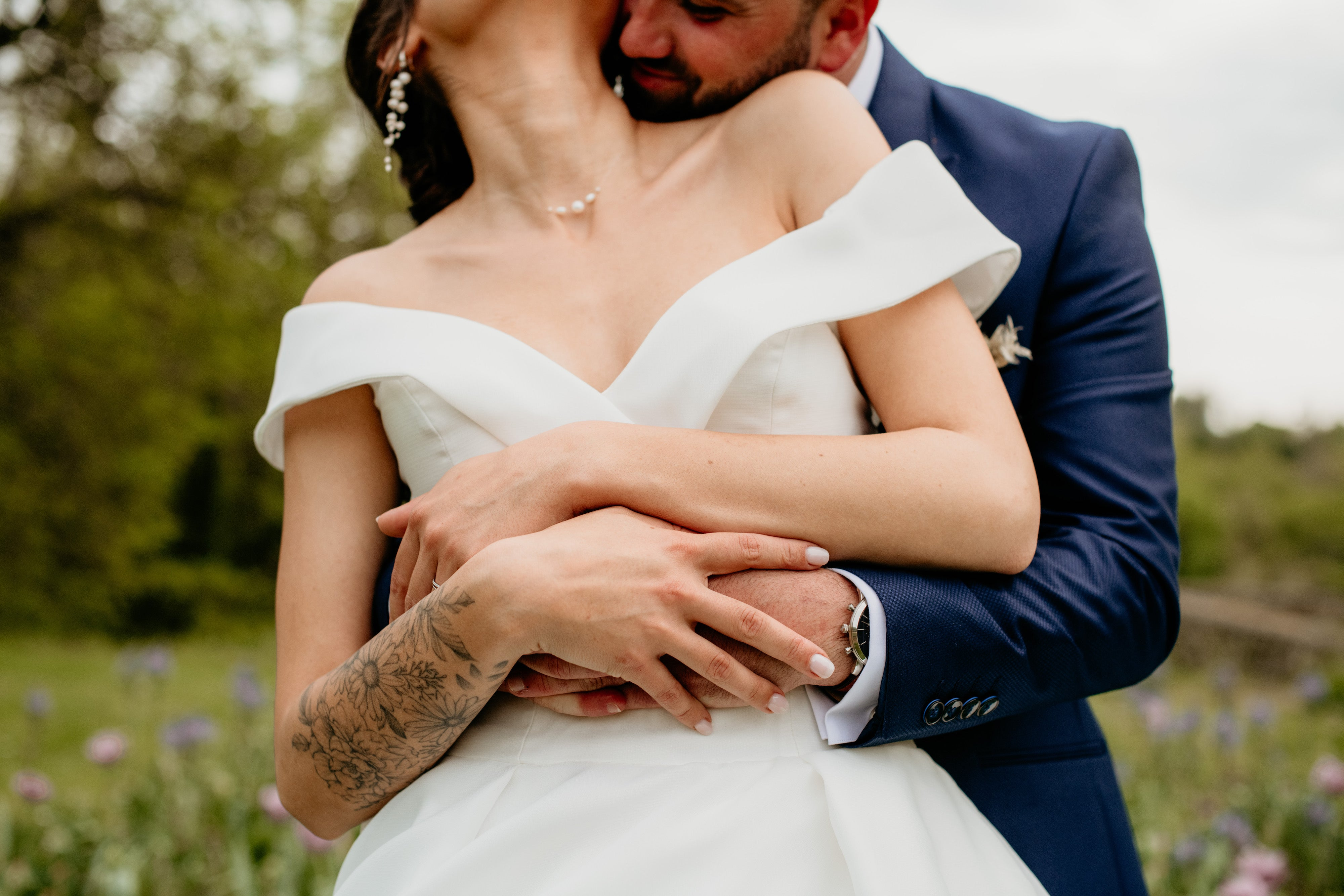 Jeune couple qui s'enlace montrant la robe de la mariée ainsi que ces accessoires de mariage en perles naturelles