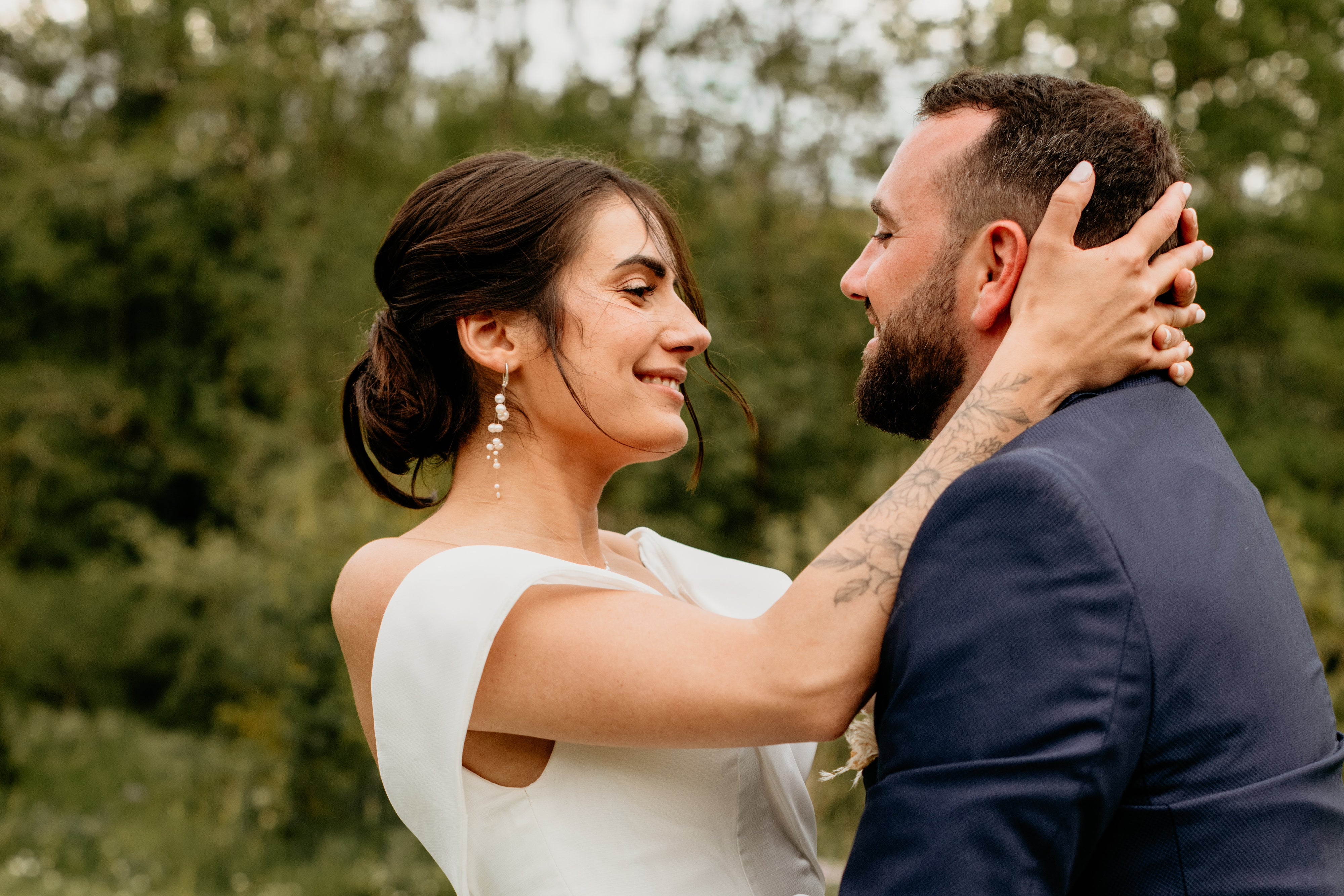 Jeune Femme de profil tenant le derrière de la tête de son époux en  montrant ces boucles d'oreilles en perles naturelles