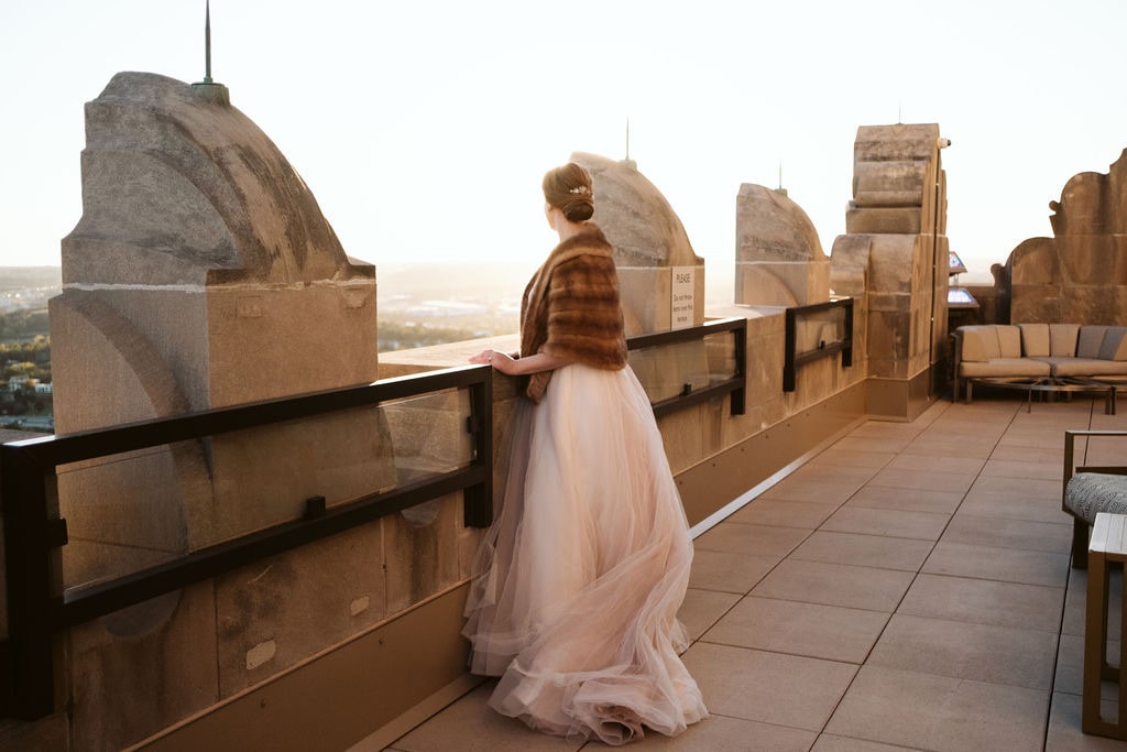 Mariée regardant l'horizon portant un chal en fourrure au dessus de sa robe de mariage