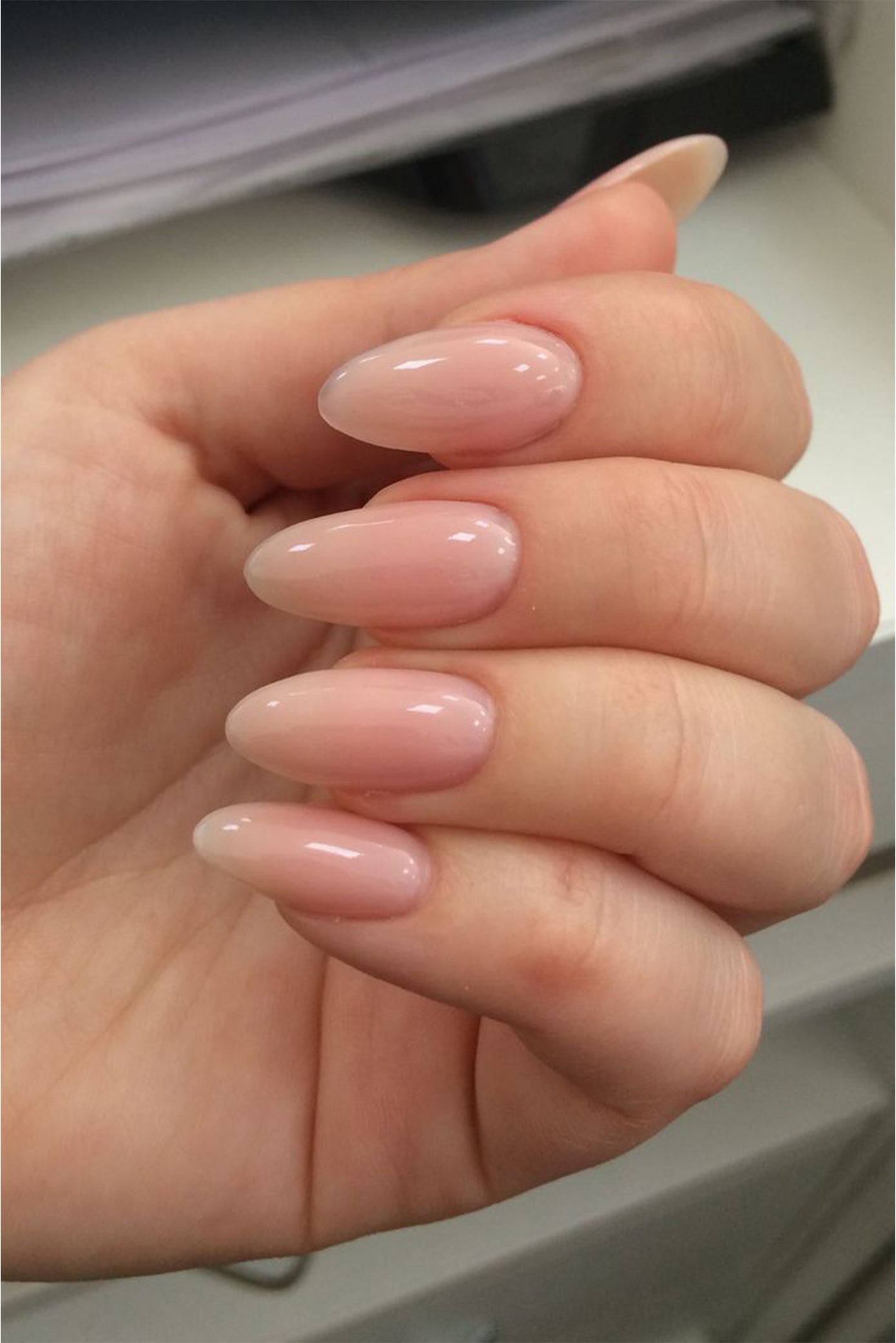 Gros plan sur les longs ongles style amande avec une couleur nude parfait pour les mariées