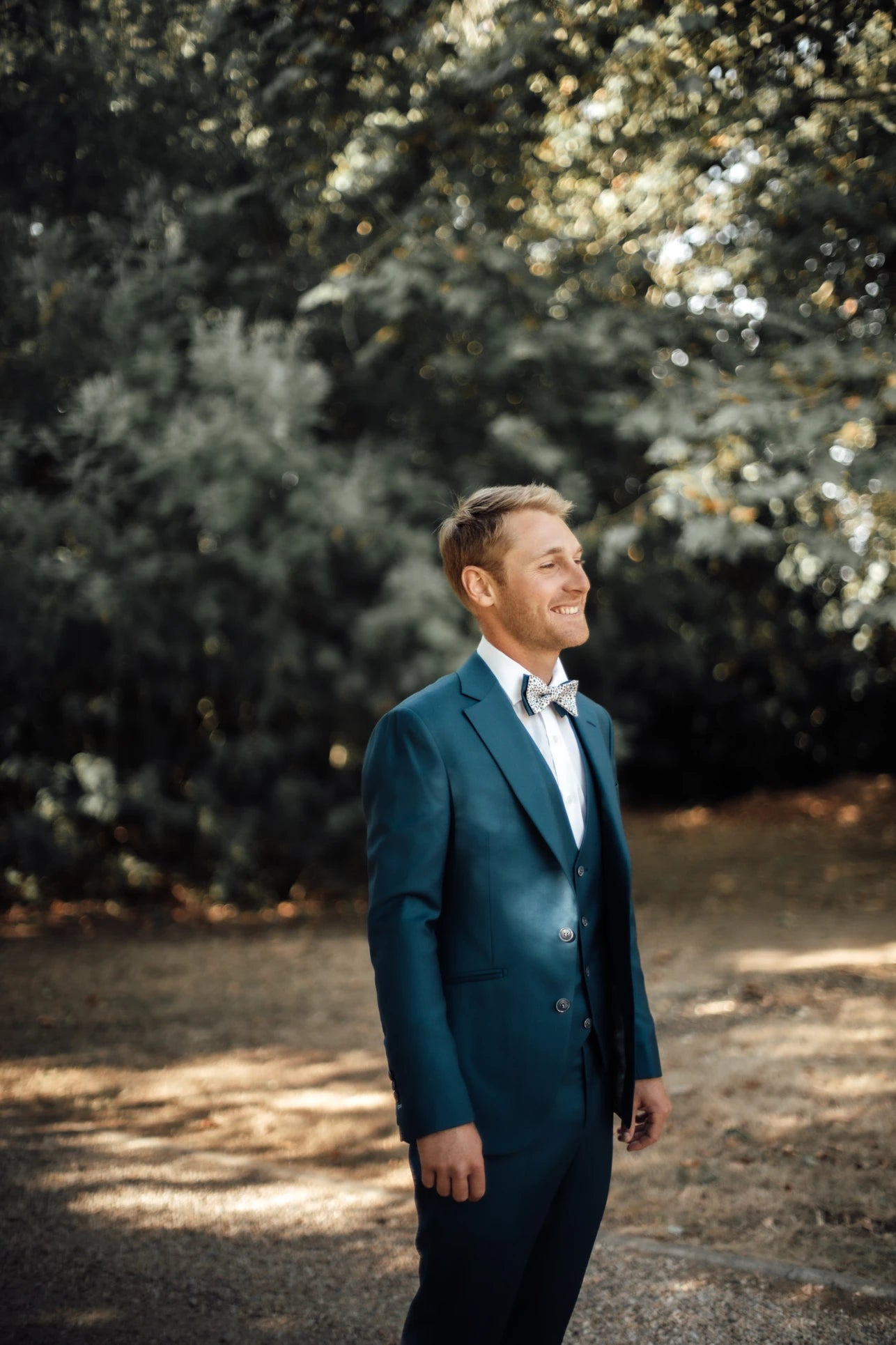 Jeune homme souriant dans son costume pour son mariage de profil par rapport à l'appareil photo 