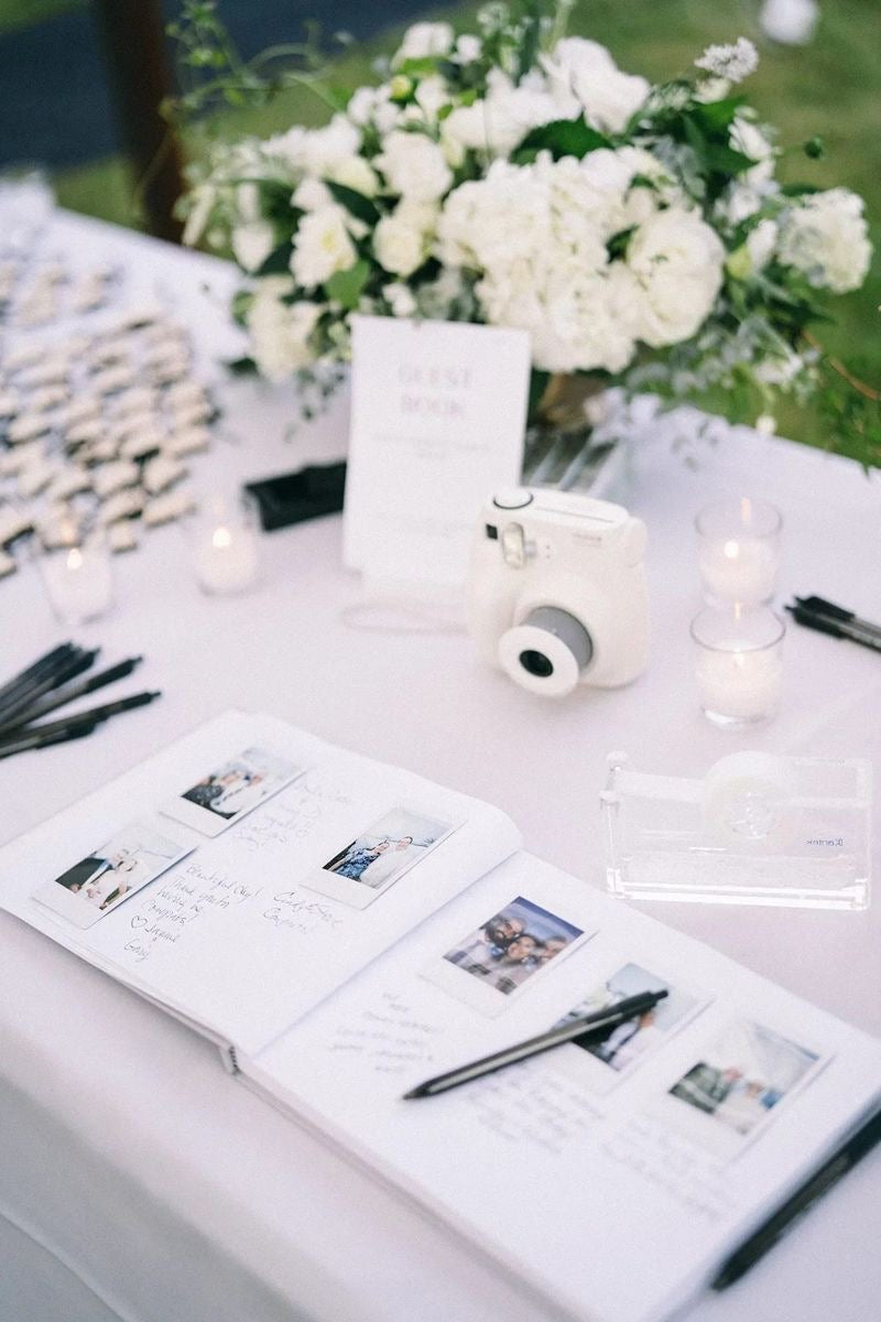 table blanche avec un livre d'or mariage à remplir avec des photos polaroid et l'appareil est à coté