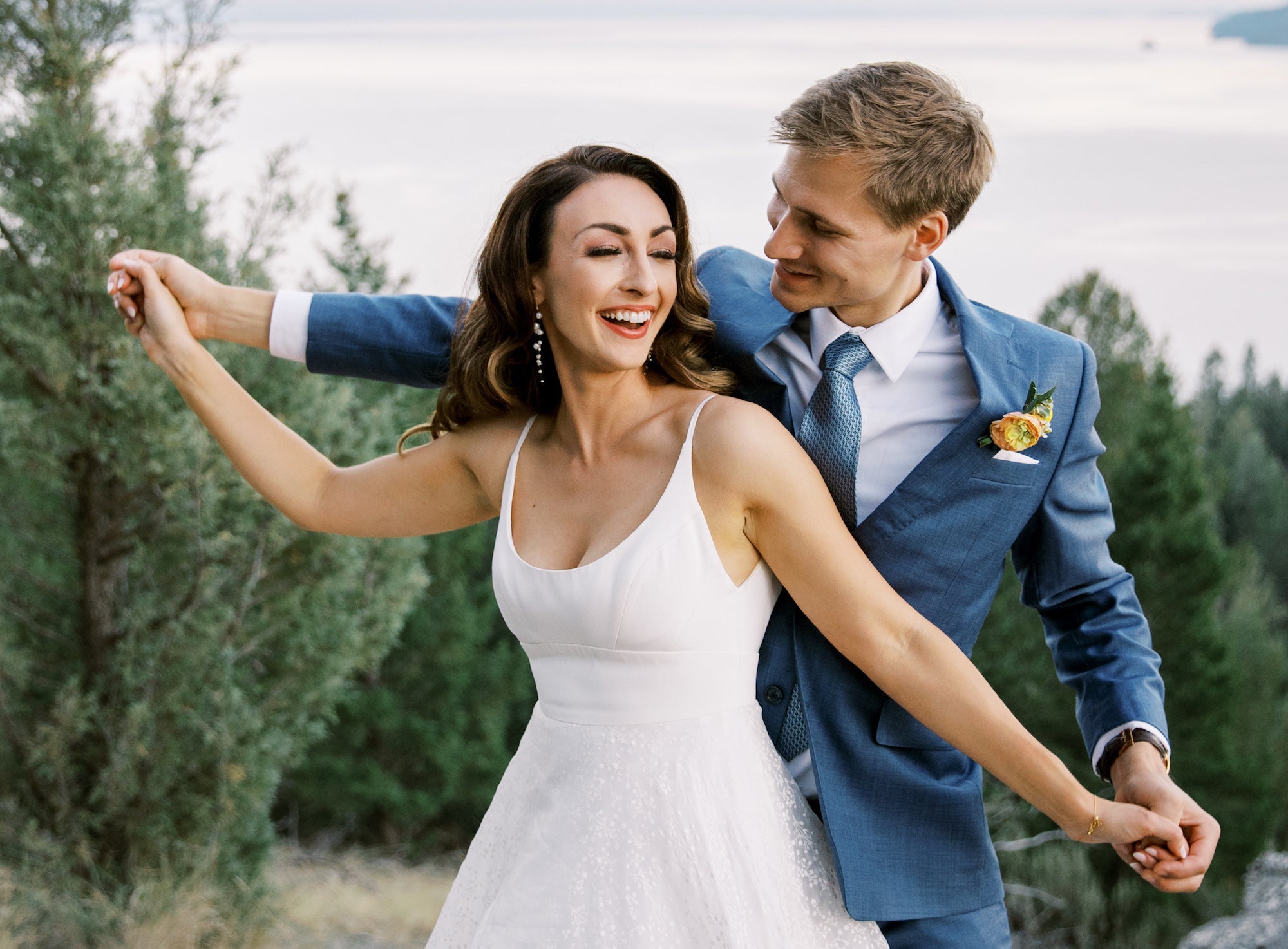 Jeune mariés se tenant la mains avec un grand sourire montrant leurs tenues et bijoux pour le mariage