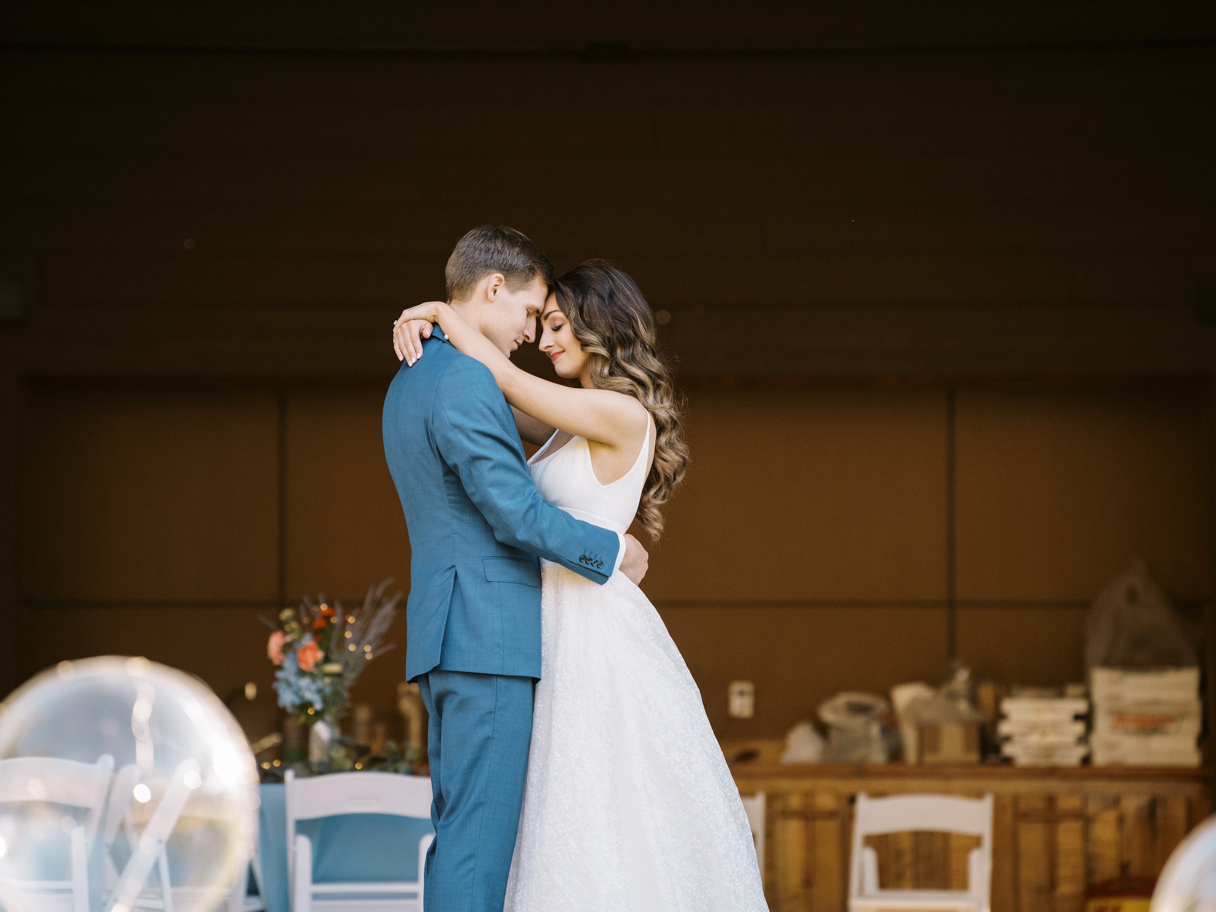 Couple de jeune mariés dansant un slow dans la salle de cérémonie de leur mariage