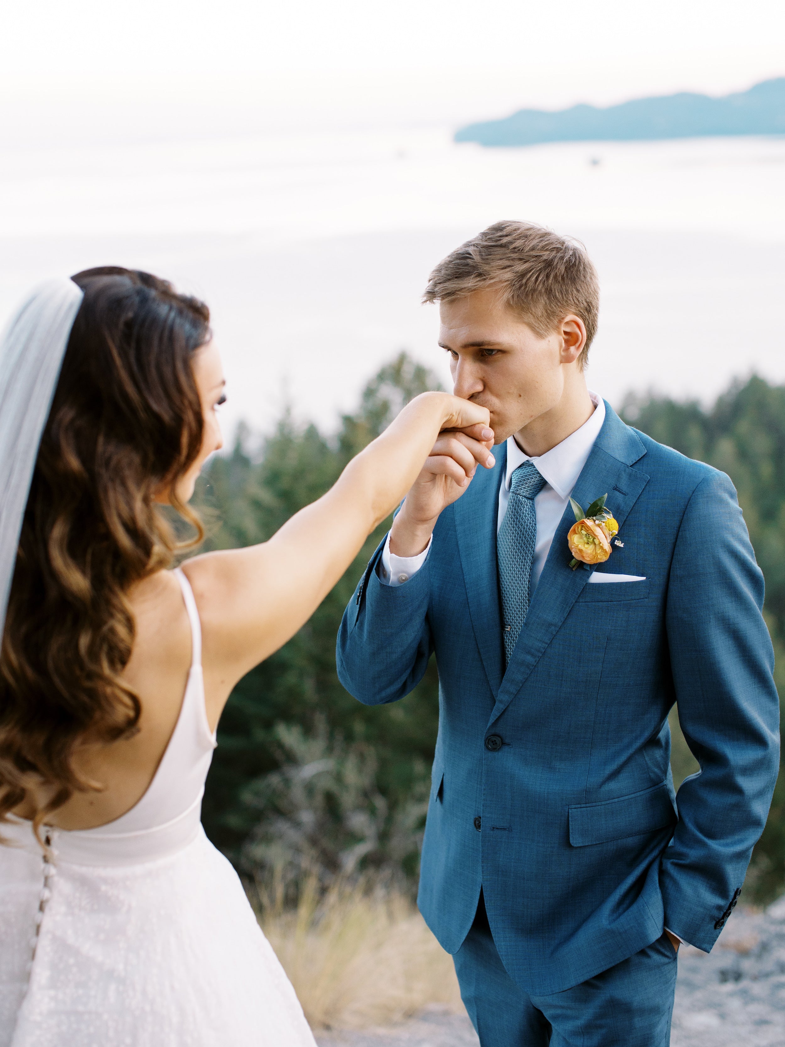 Homme baisant la main d'une jeune mariée en robe blanche avec un voile